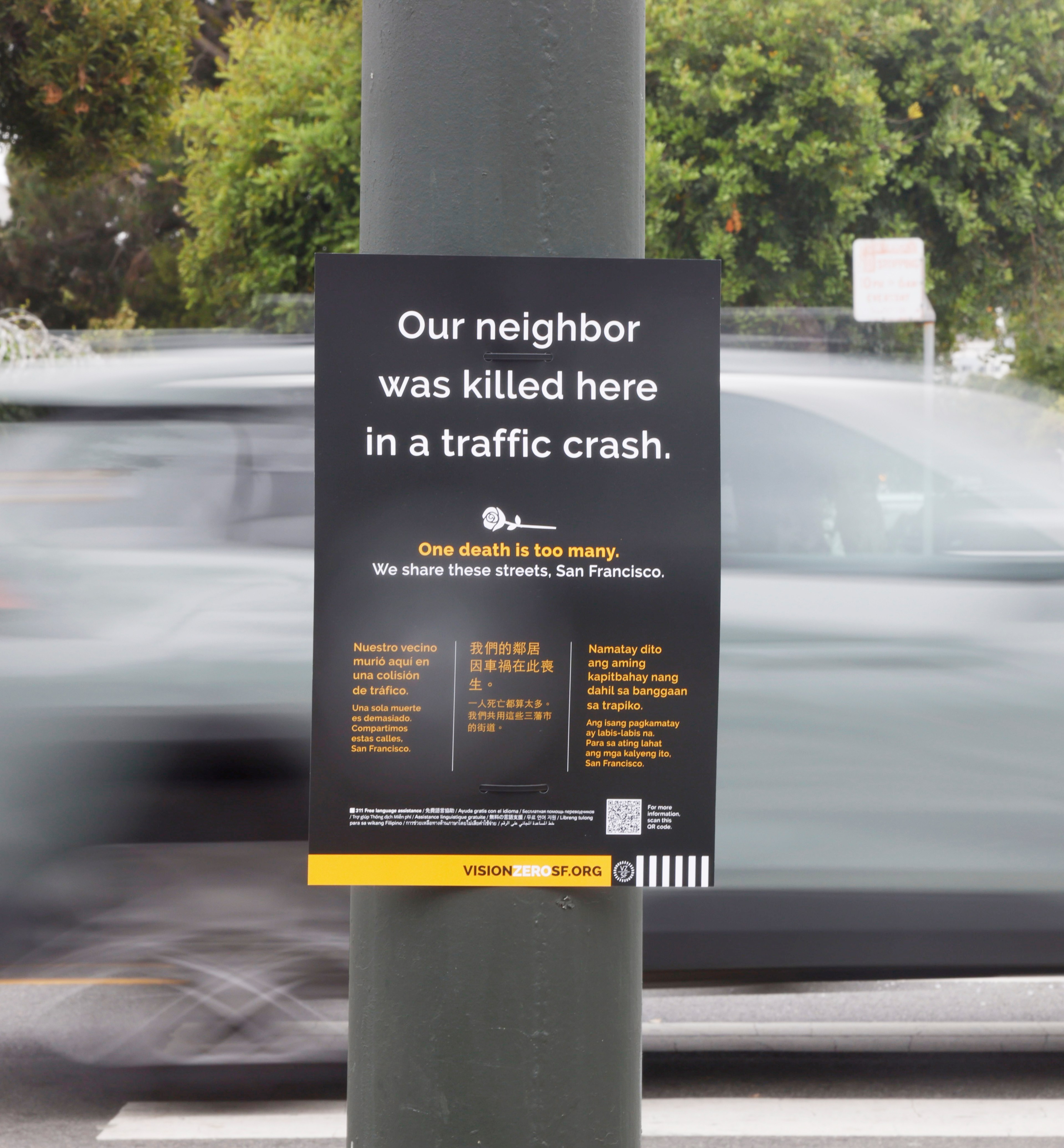 A sign on a pole reads, &quot;Our neighbor was killed here in a traffic crash. One death is too many. We share these streets, San Francisco,&quot; in multiple languages.