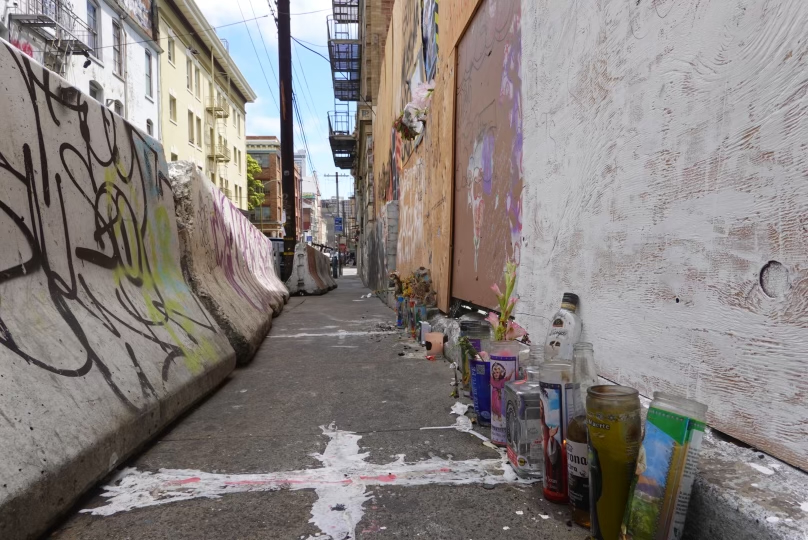 a cross painted in wax next to empty beer bottles and candles