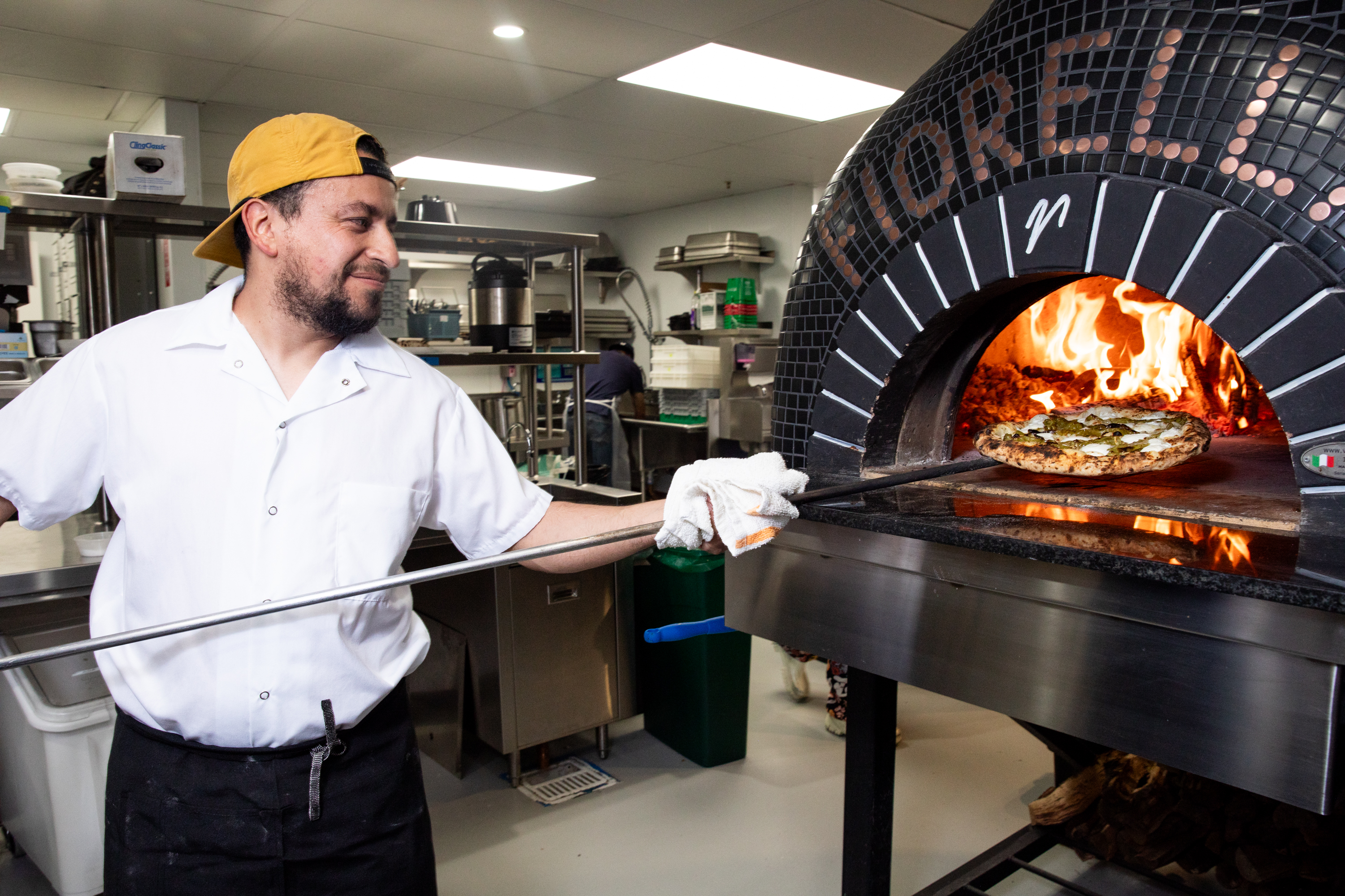 A chef pulls a pizza out of the oven.