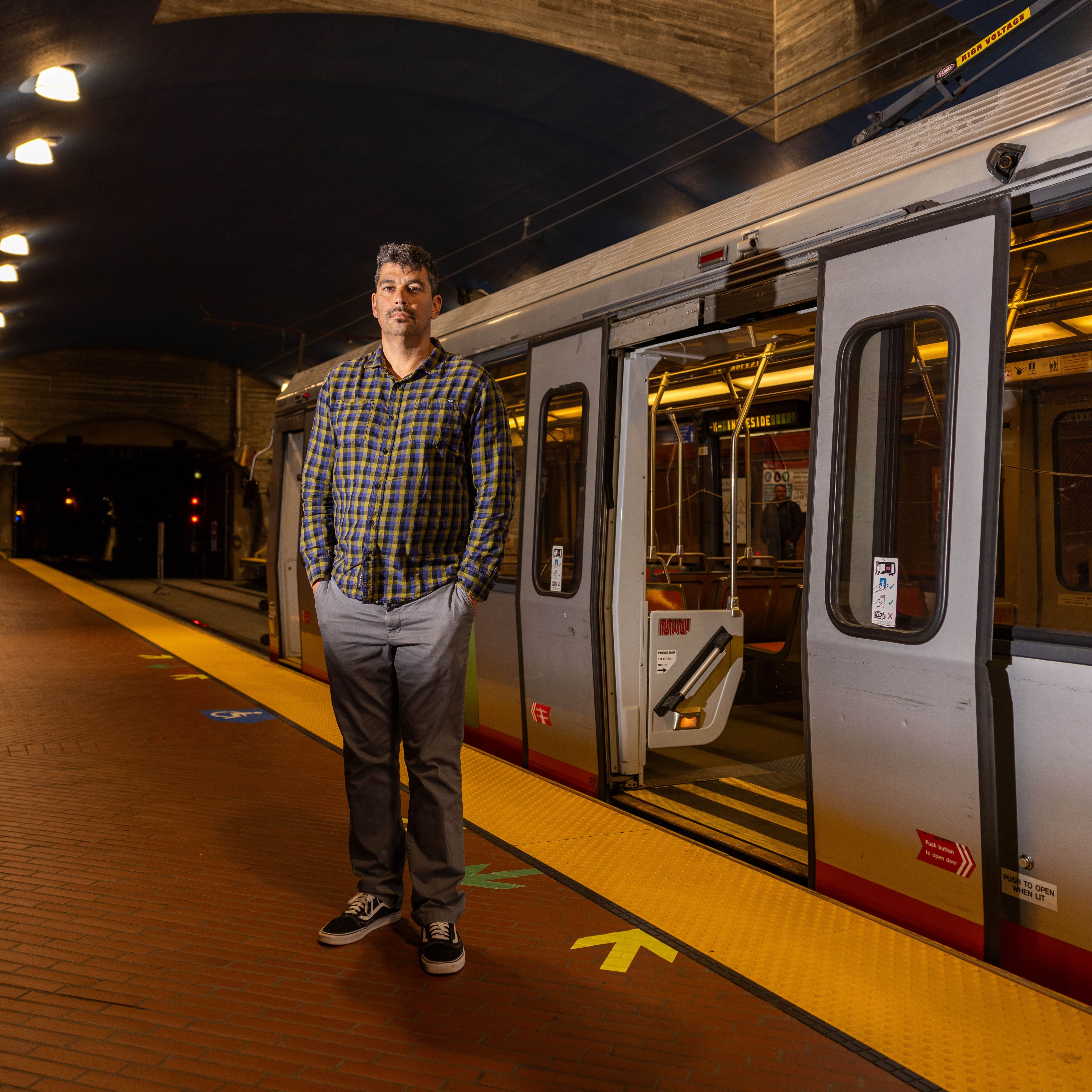 Man stands in front of light rail vehicle.