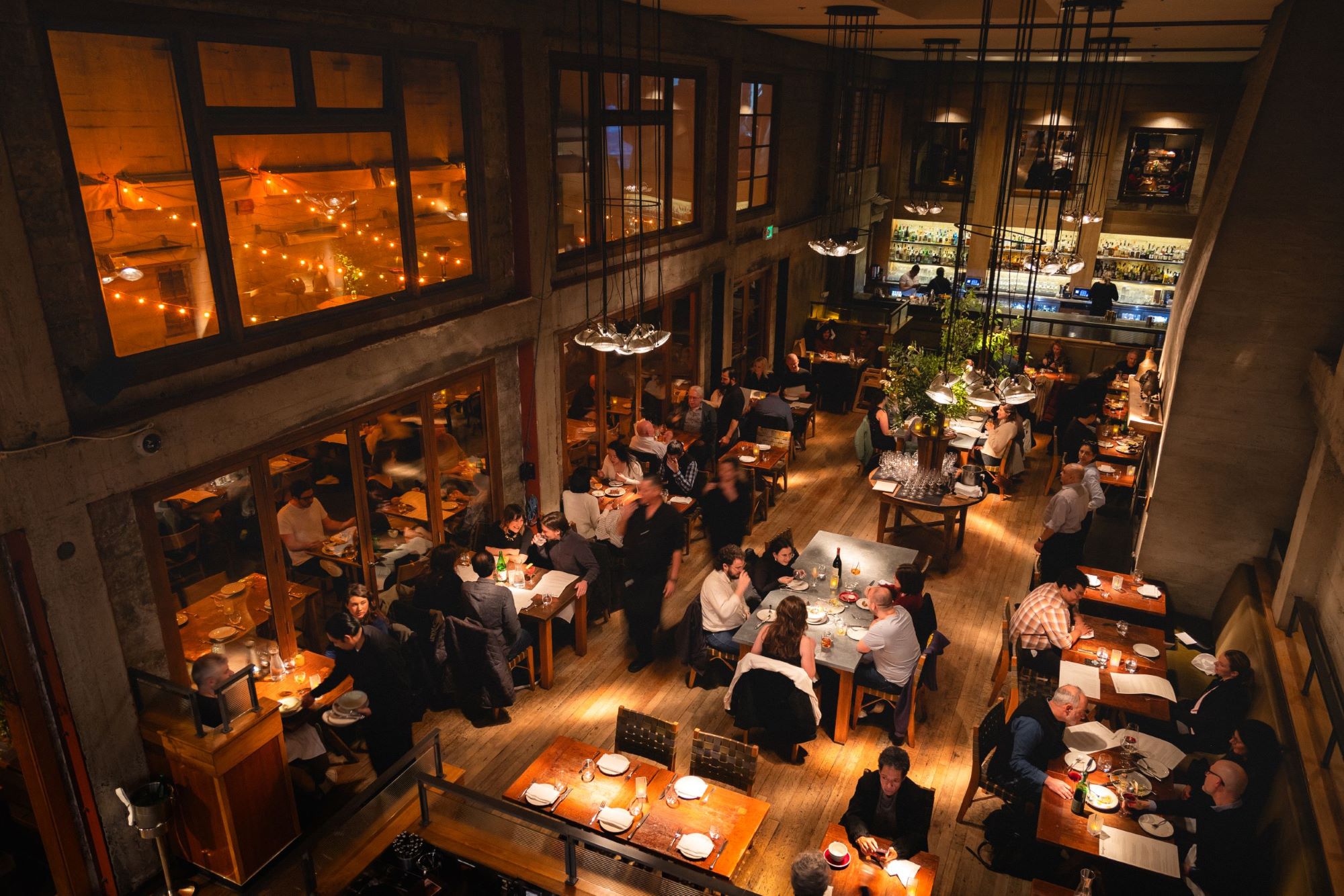 A view of the dining room at Foreign Cinema from above including tables of diners enjoying food and drinks.