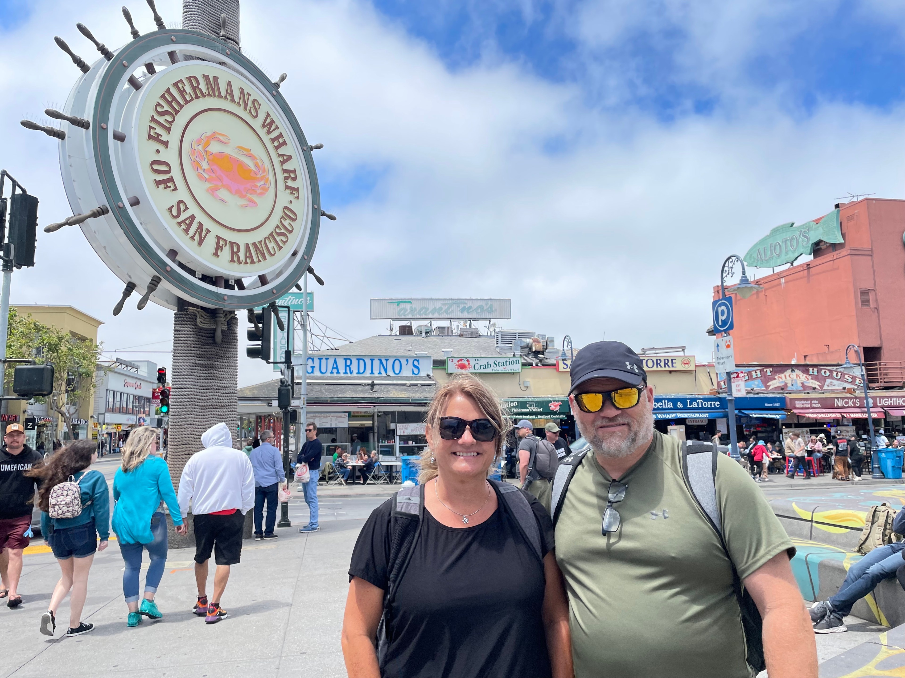 Tourists stroll down a San Francisco pier lined with shops and restaurants.