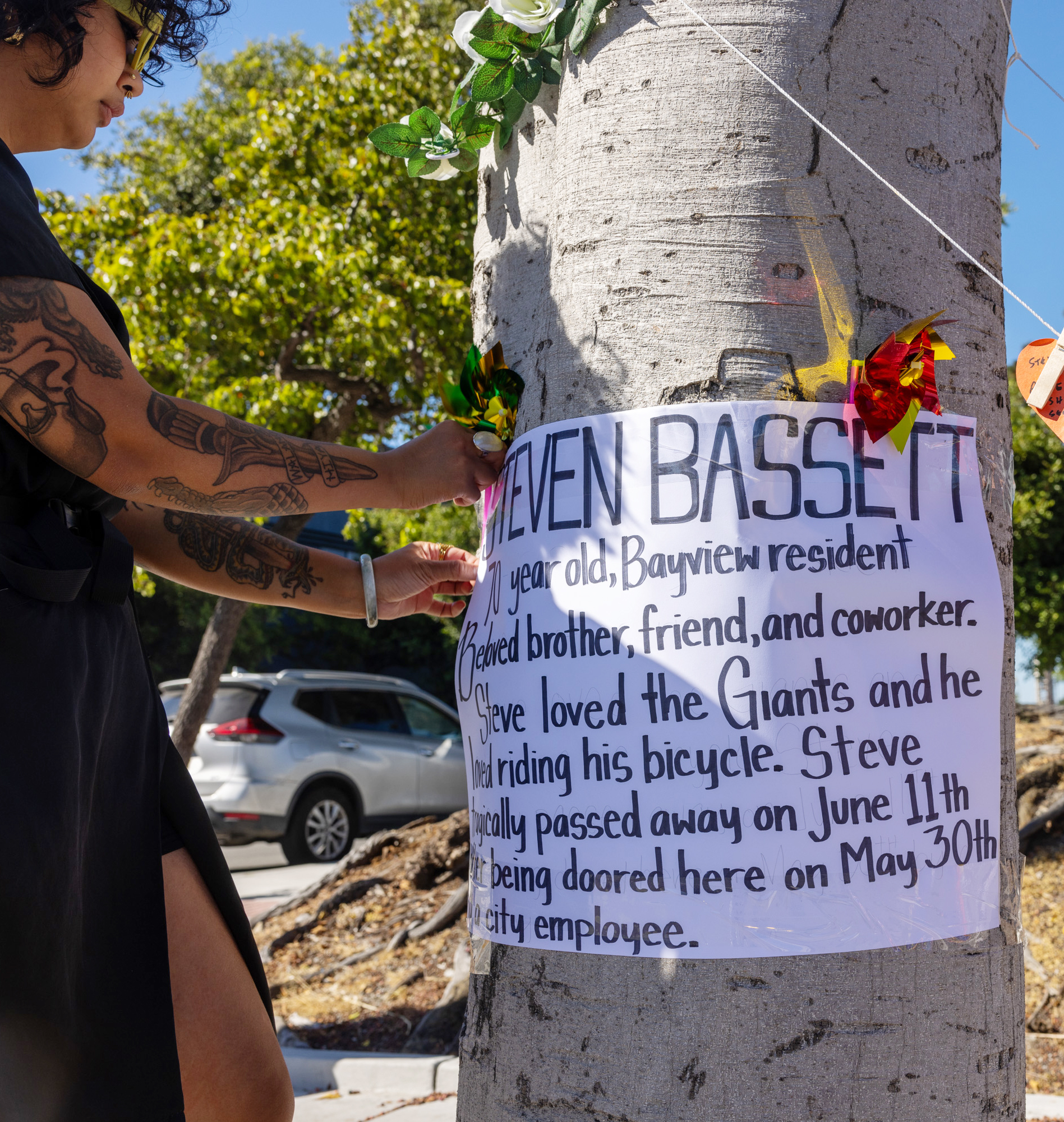 A person pins a poster to a tree.