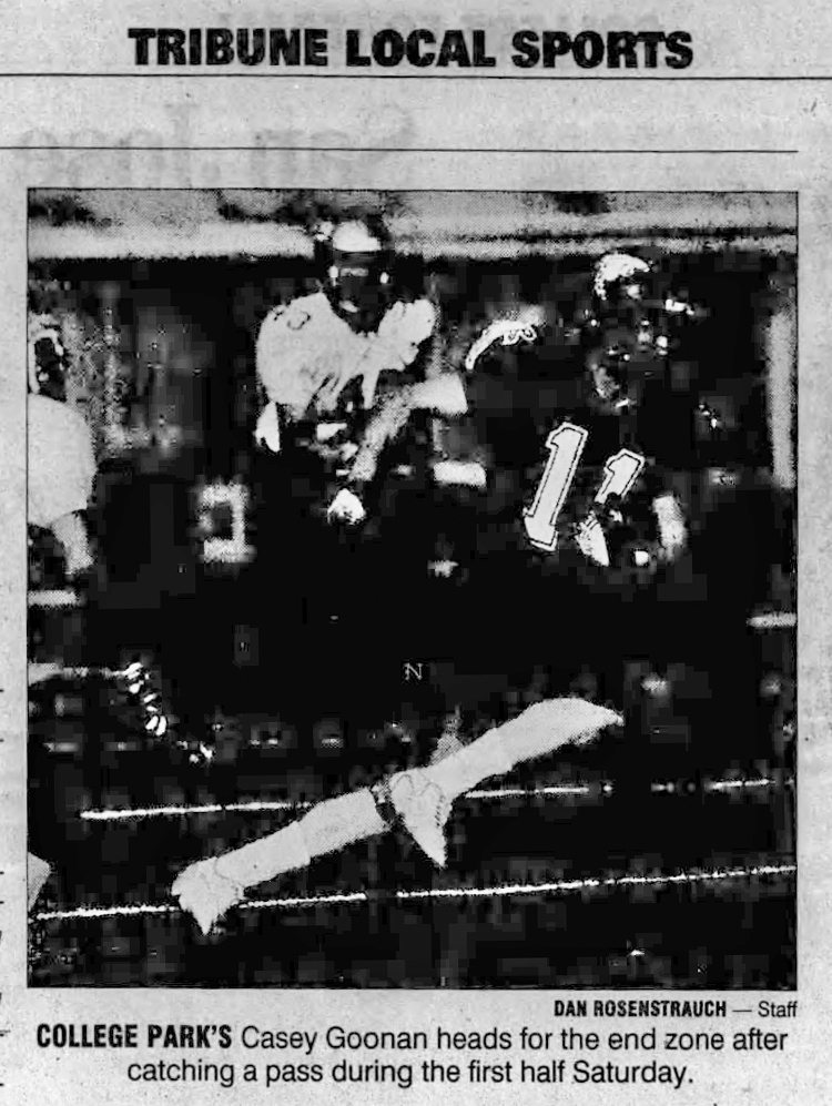 The image shows a black-and-white photograph of a football game from a local sports section. A player, number 11, runs toward the end zone after catching a pass.