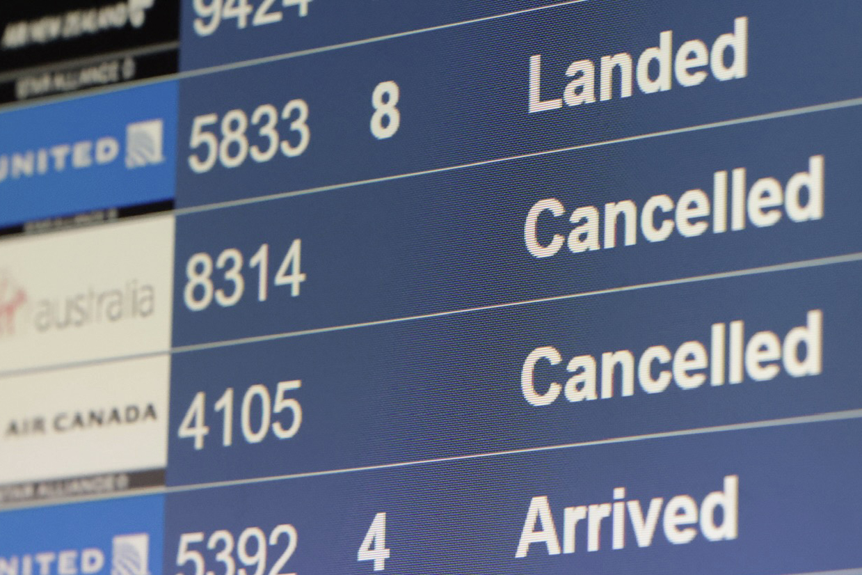 The image shows an airport flight information board. It lists flight statuses, including &quot;Landed,&quot; &quot;Cancelled,&quot; and &quot;Arrived&quot; for several airlines like United and Air Canada.