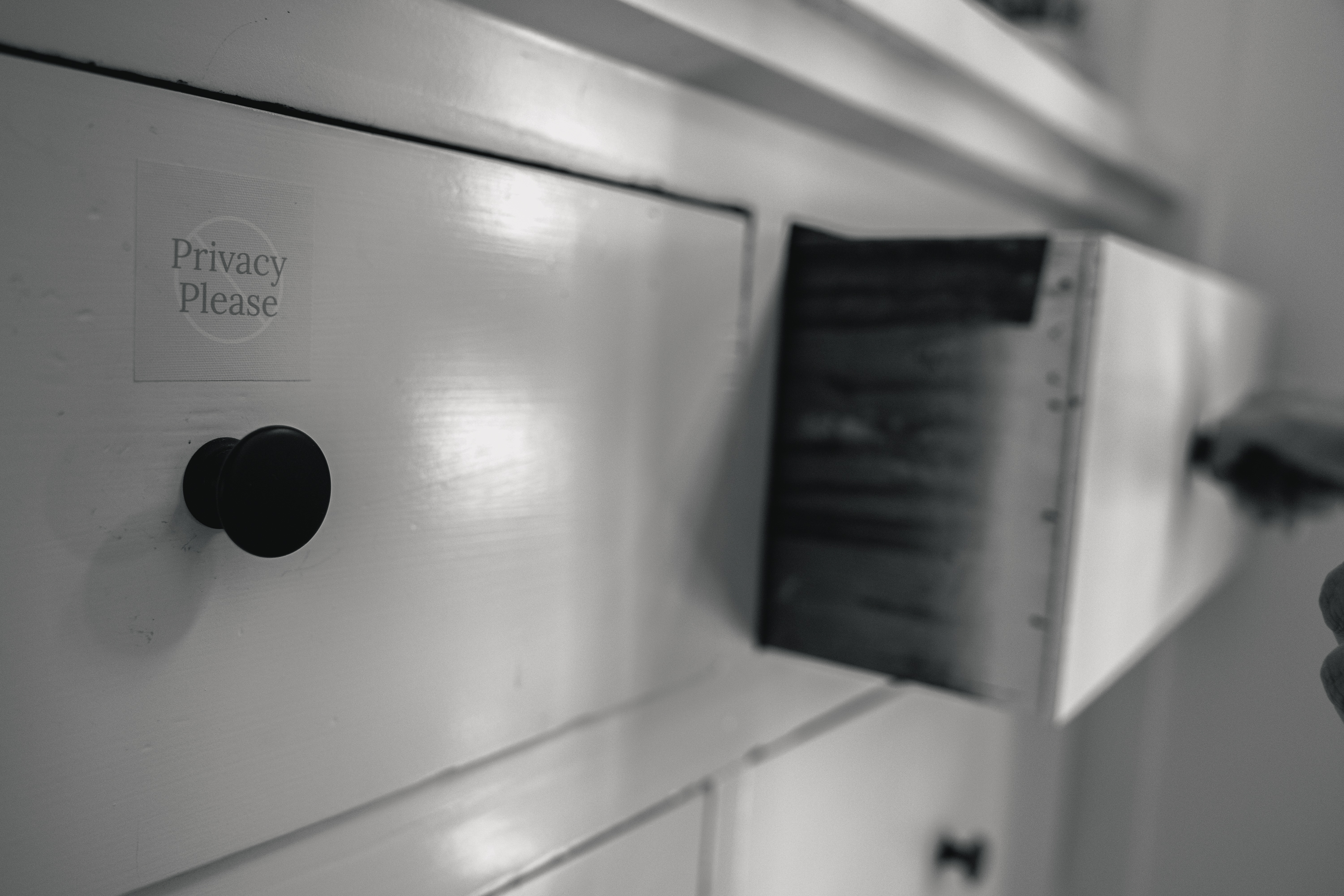 The image shows a white cabinet with black knobs and one drawer partially open. A small sign on the drawer says, &quot;Privacy Please.&quot;