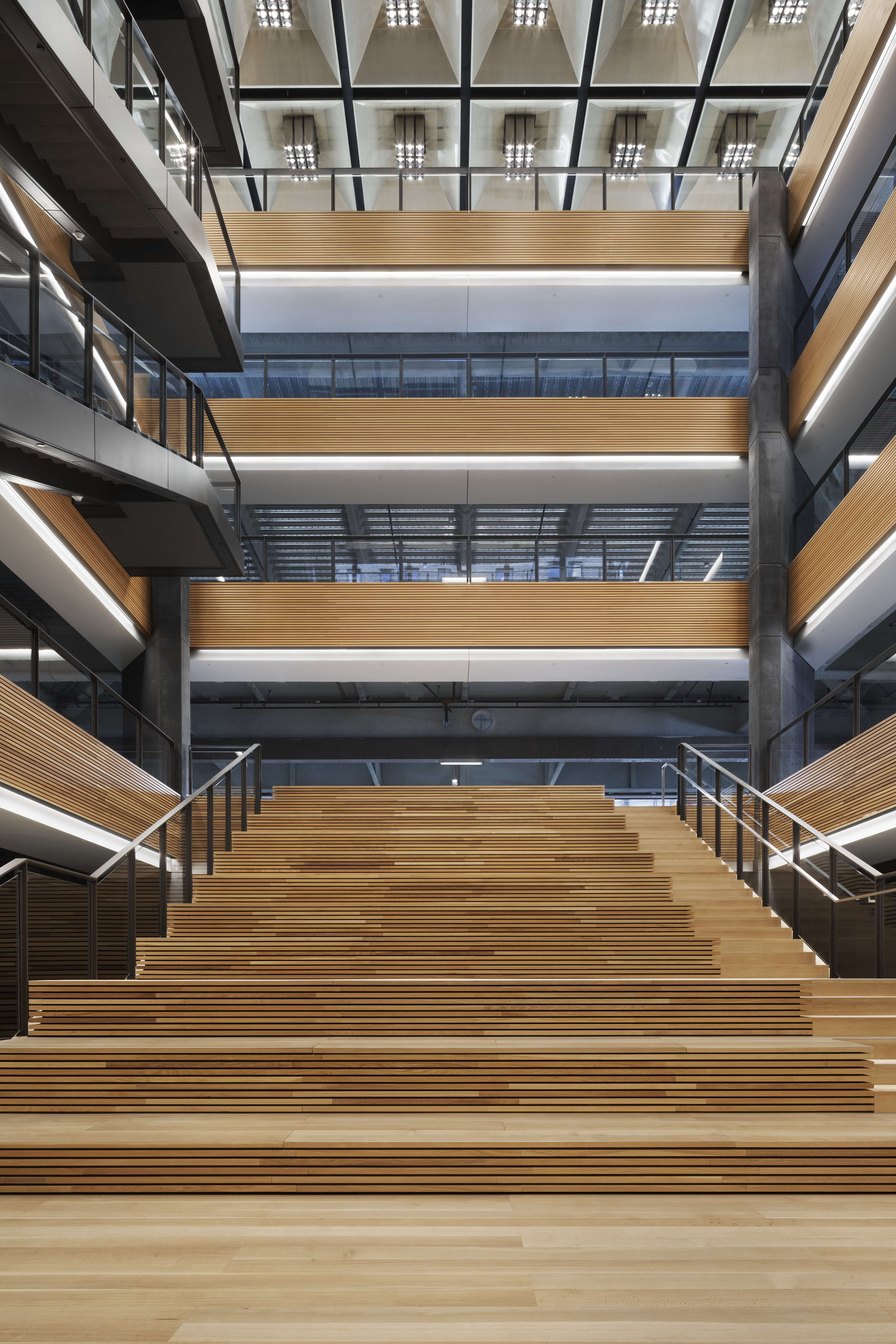 A three-story atrium of wood is illuminated by light.