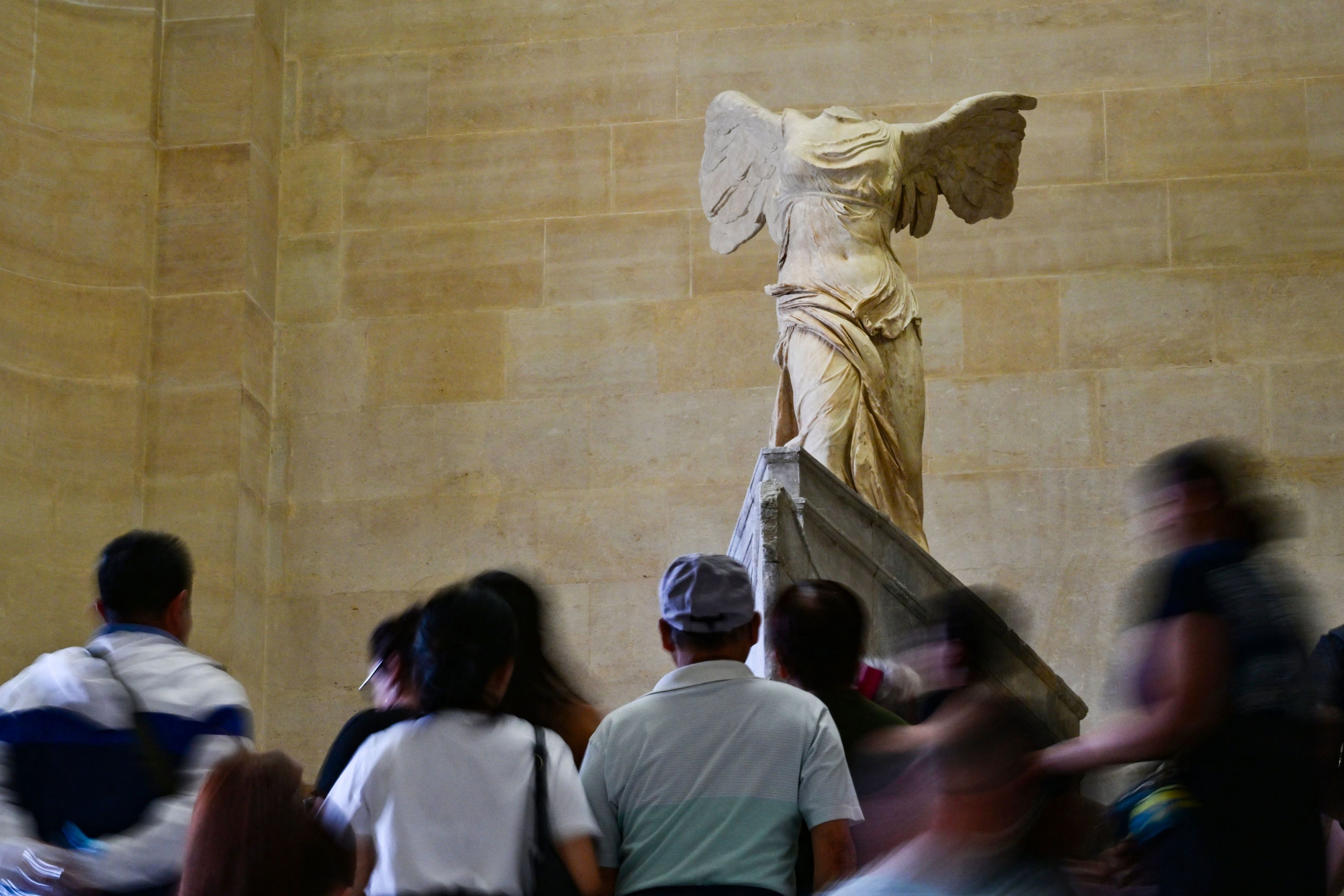 People are gathered beneath a statue with wings.