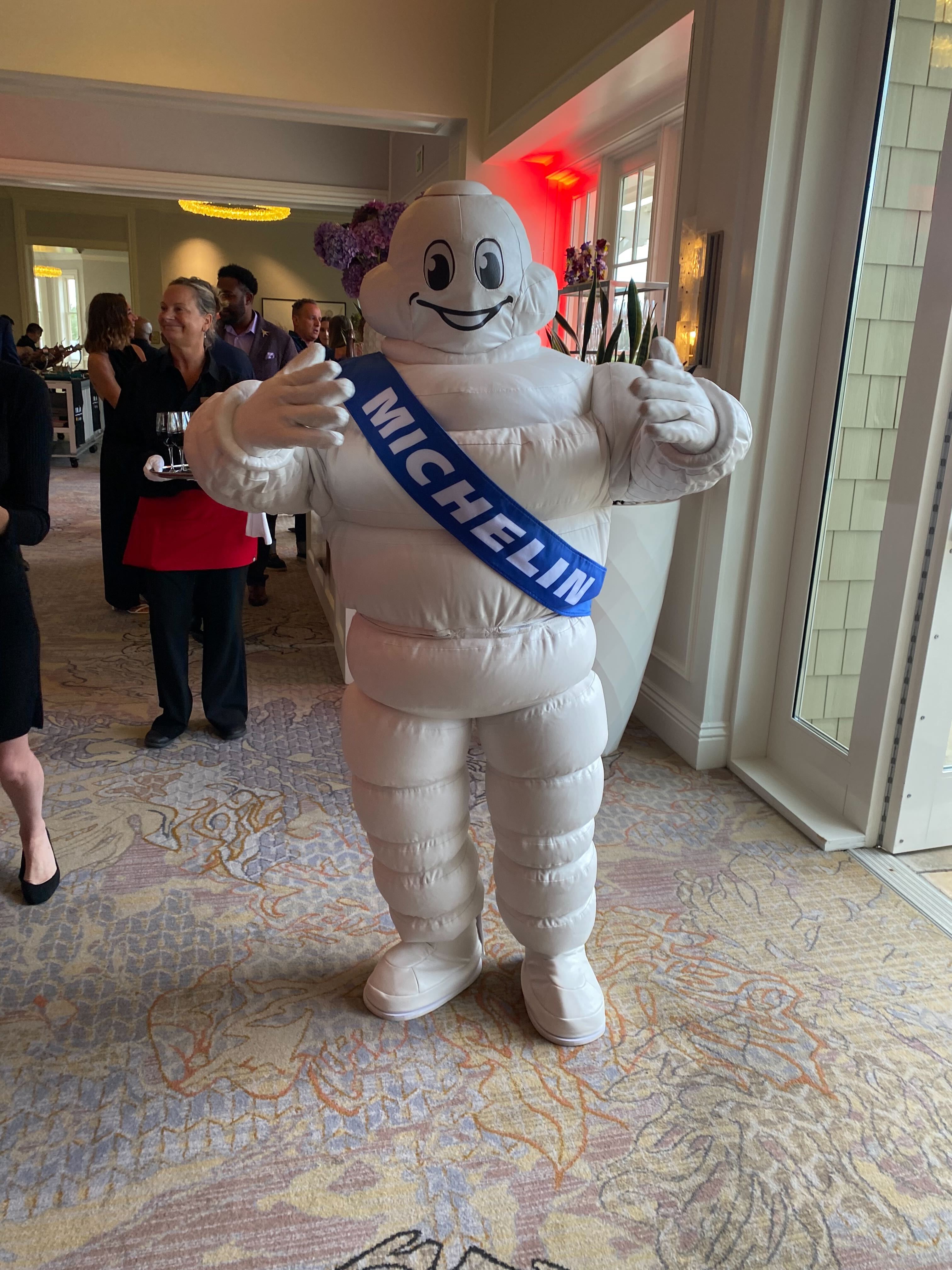 A person in a while costume of the "Michelin Man," the official mascot of the Michelin tire company.