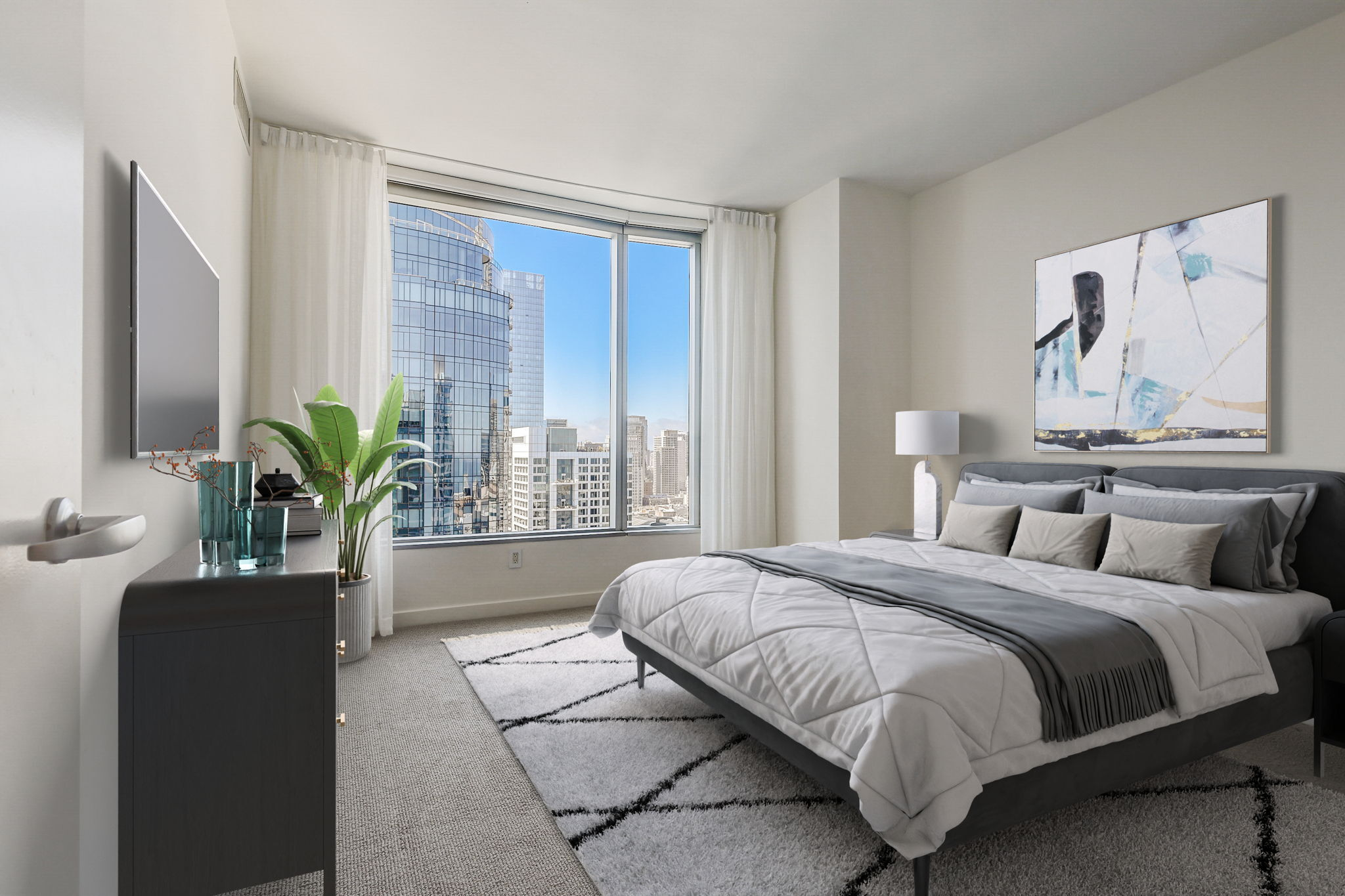 The image shows a modern bedroom with a large window providing a city view, a double bed with gray and white bedding, a flat-screen TV, a plant, and contemporary decor.