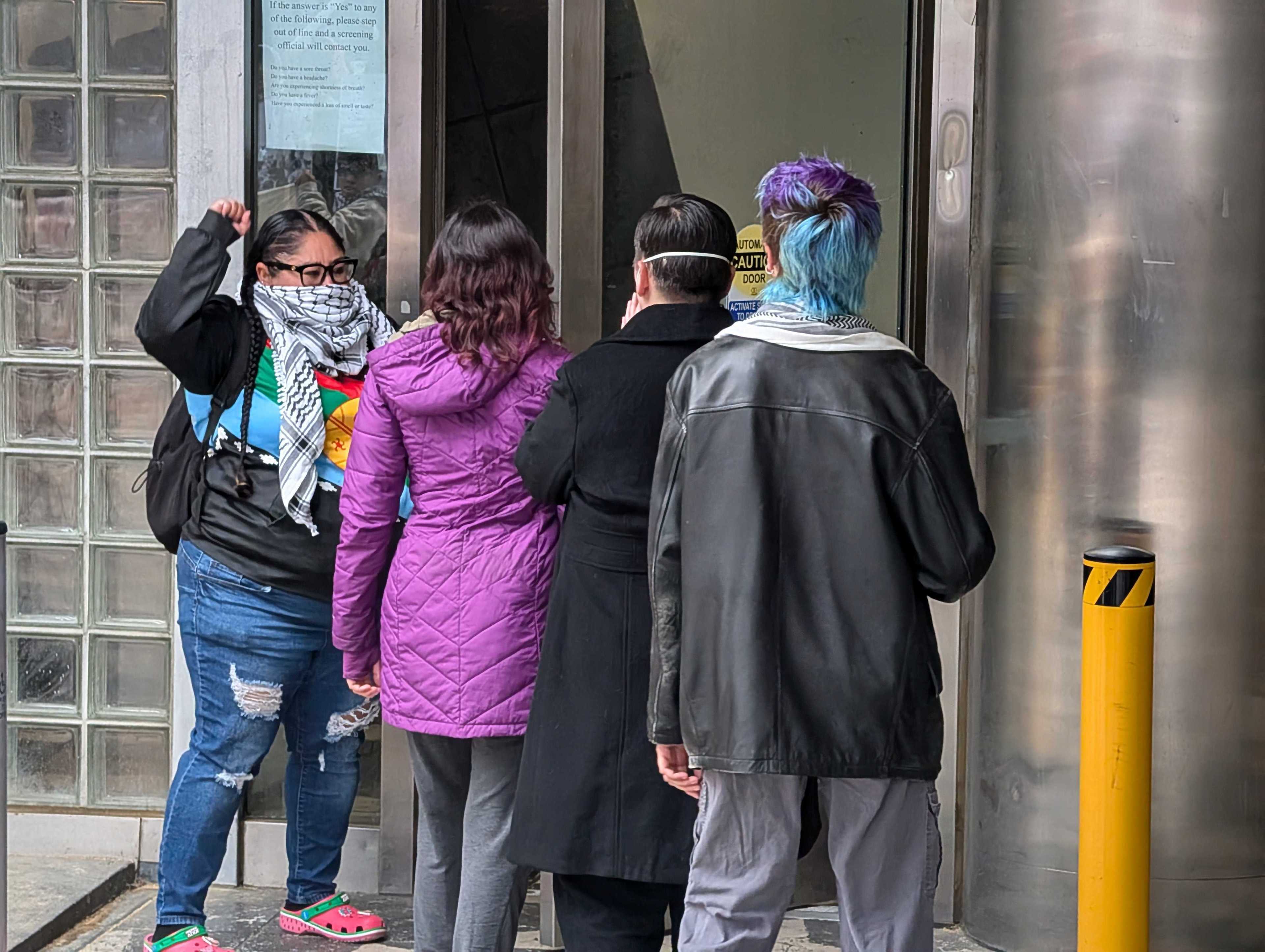 A group of several people stand in line to enter through the front doors of the San Francisco sheriff's department.