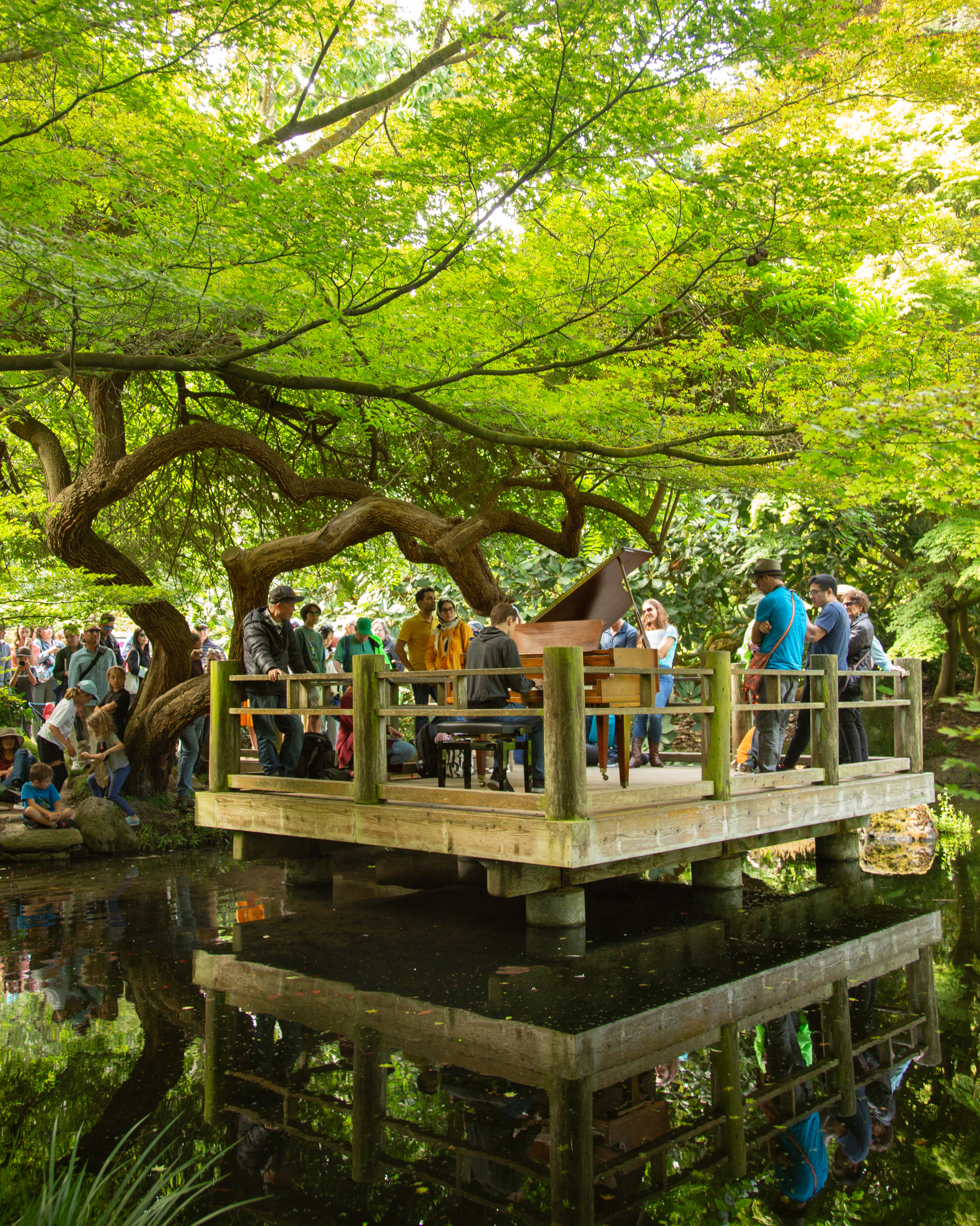 People stand around a piano in a treehouse.