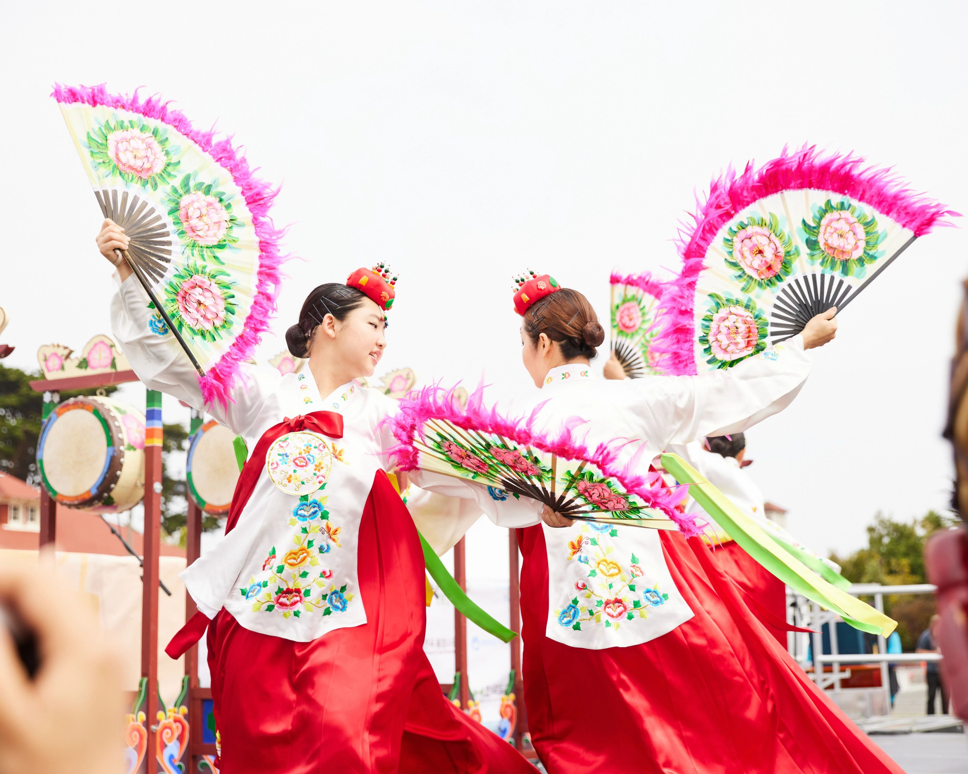 Two women in traditional Korean clothing dance.