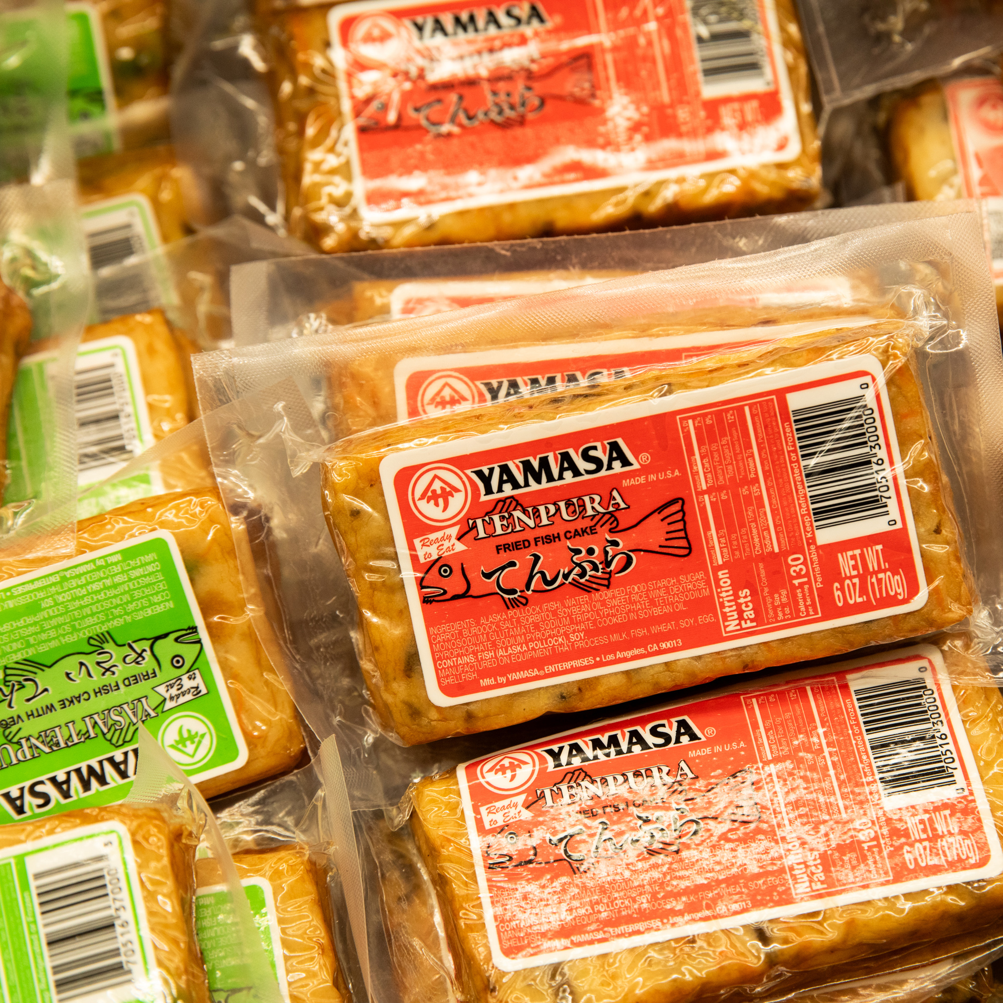 The image shows multiple packages of Yamasa Tenpura Fried Fish Cake, each in vacuum-sealed plastic with red and green labels indicating the product name and details.