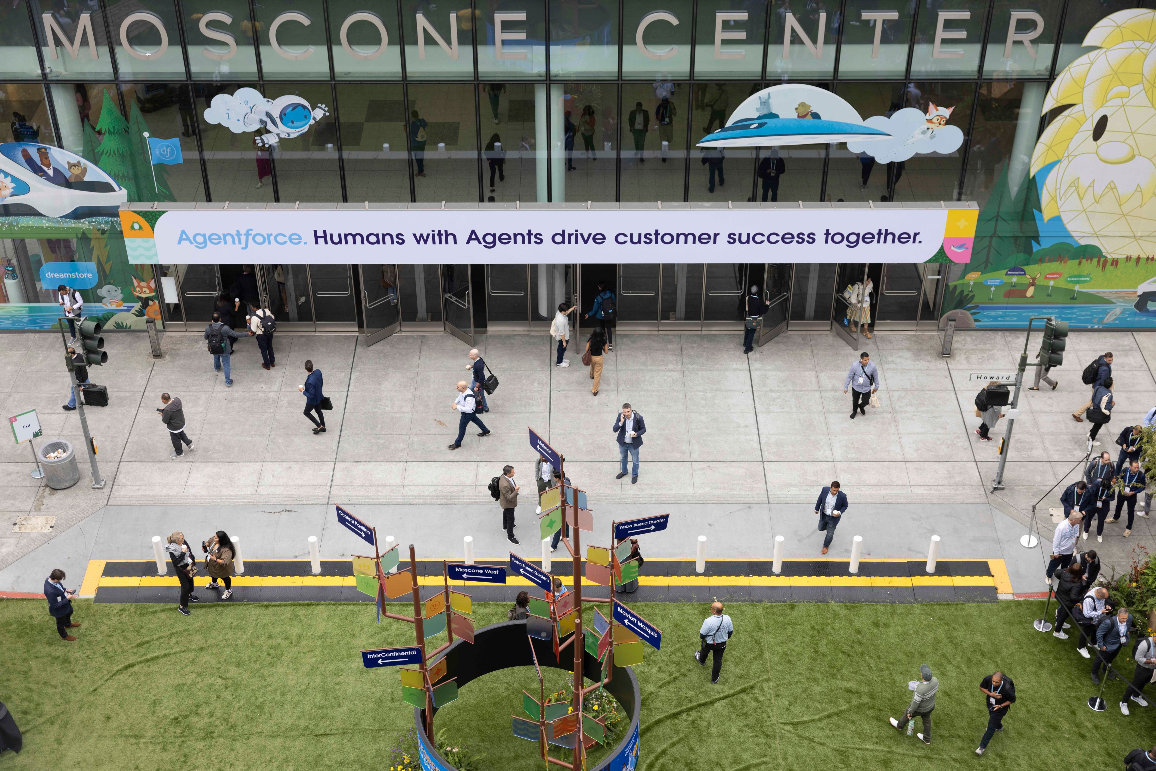 The image shows people walking in front of the Moscone Center with a large banner reading "Agentforce. Humans with Agents drive customer success together."