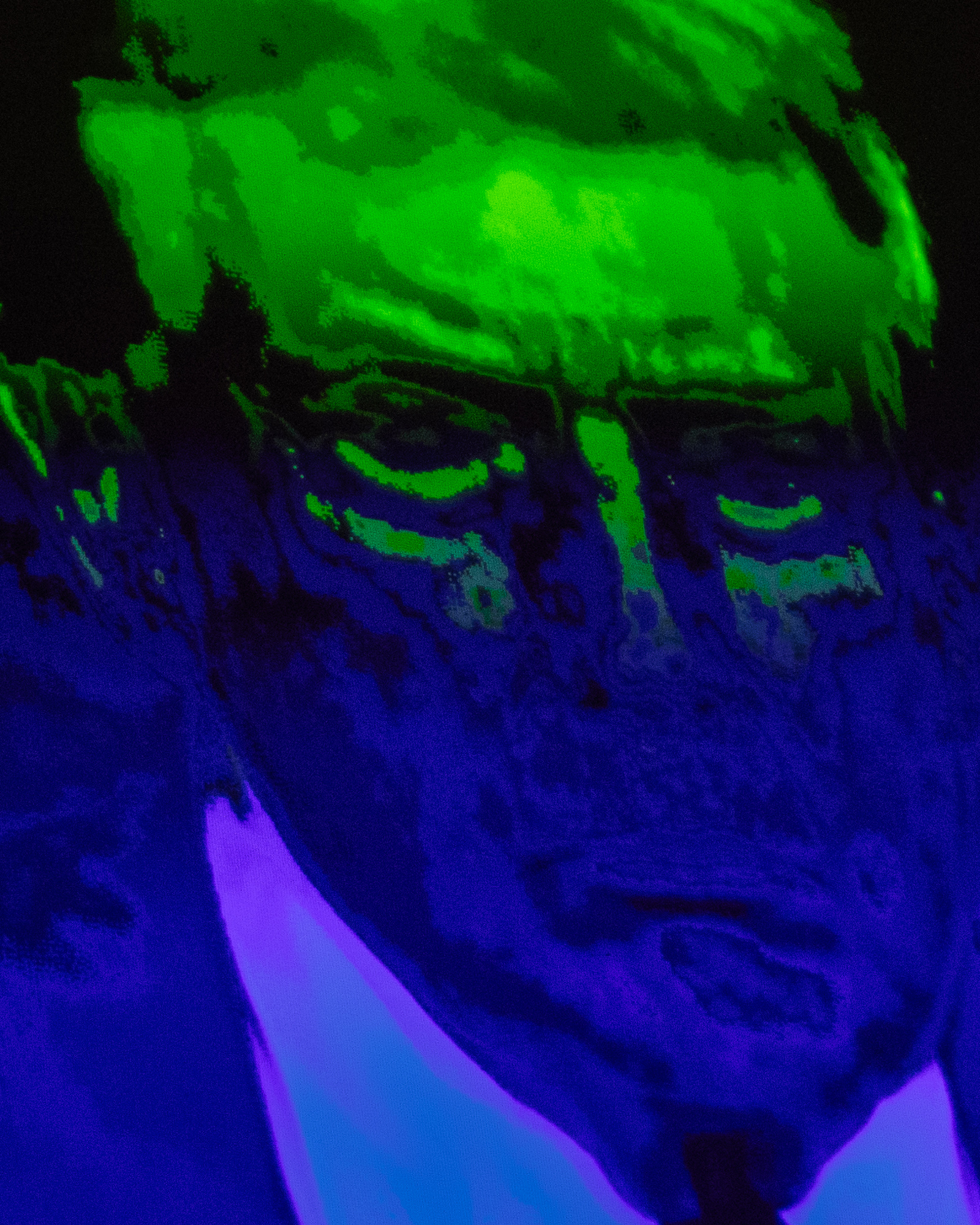 The image shows a distorted, color-enhanced face with intense green and blue hues and dark shadows, creating an eerie, abstract effect.