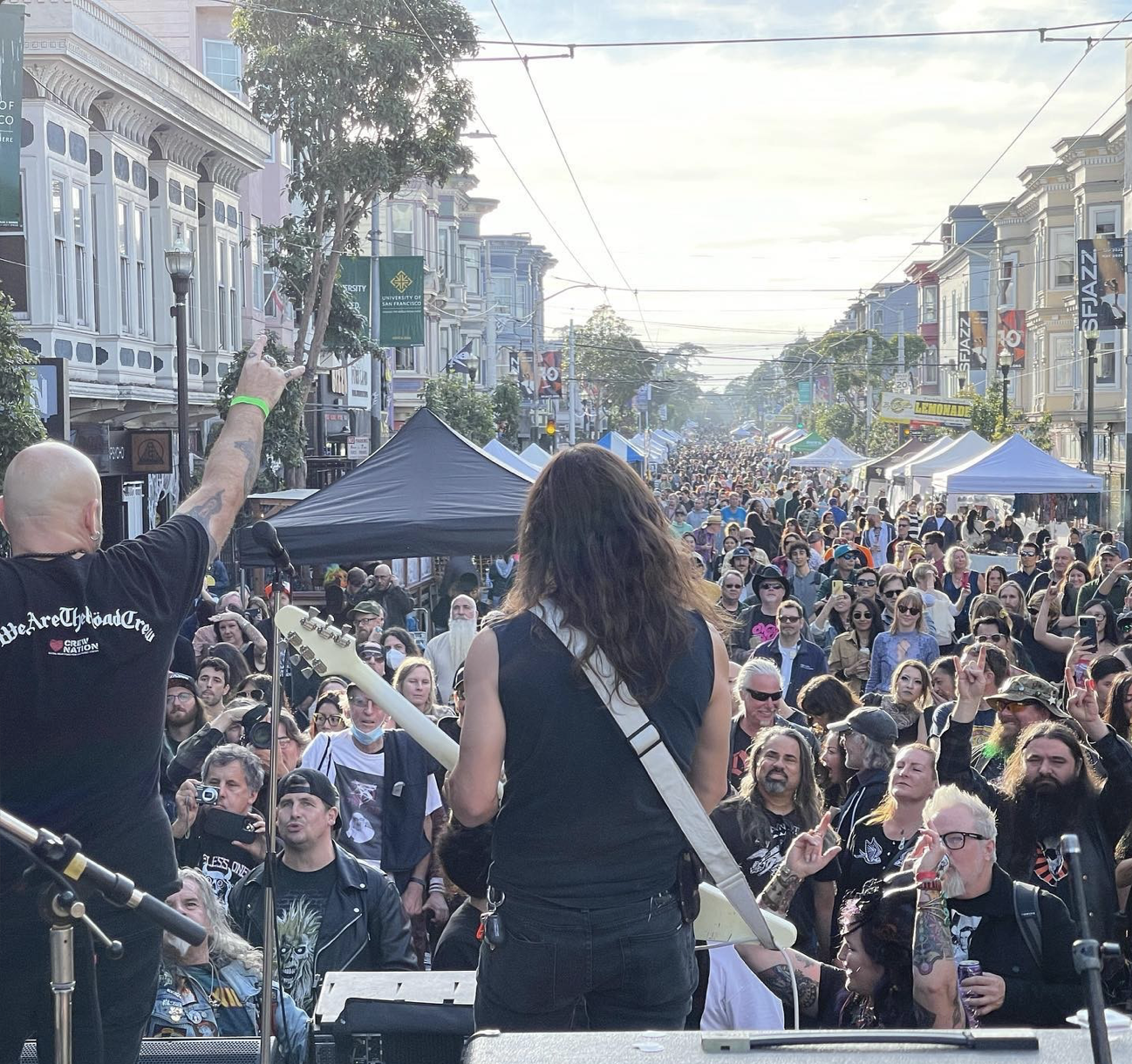 A guitarist plays in front of a crowded street.