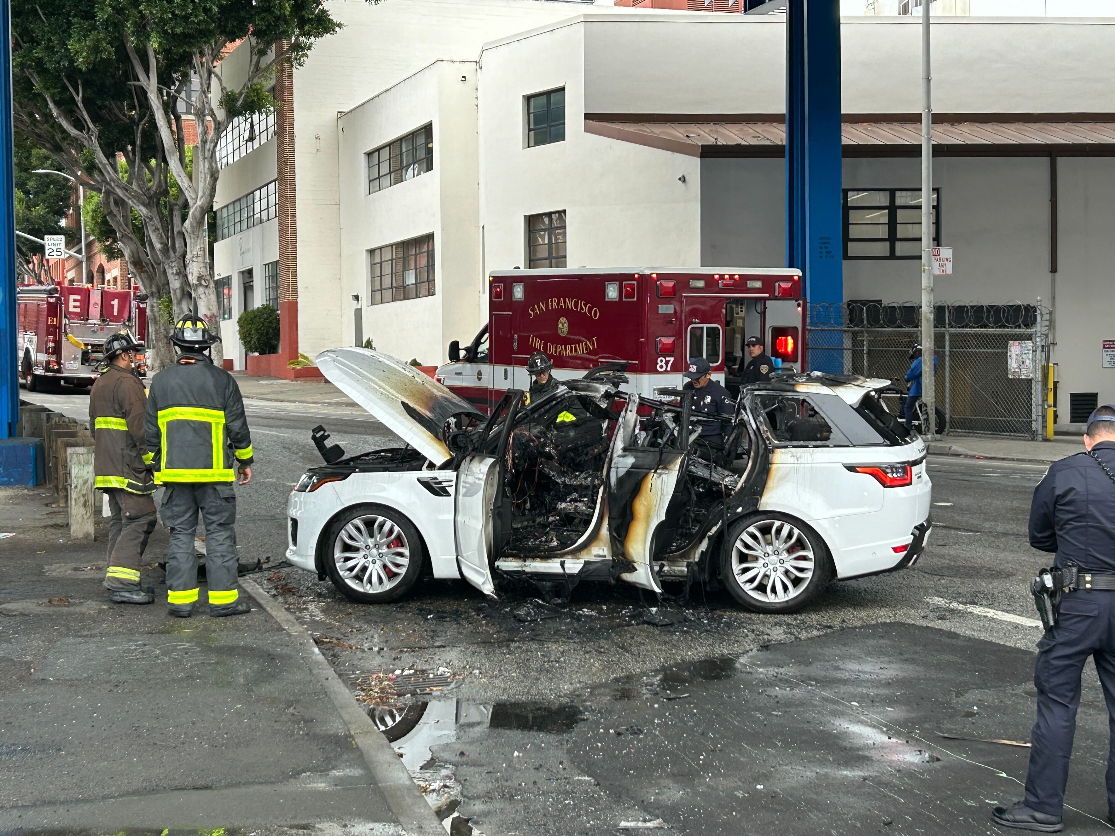 Firefighters inspect a white SUV that had caught fire.