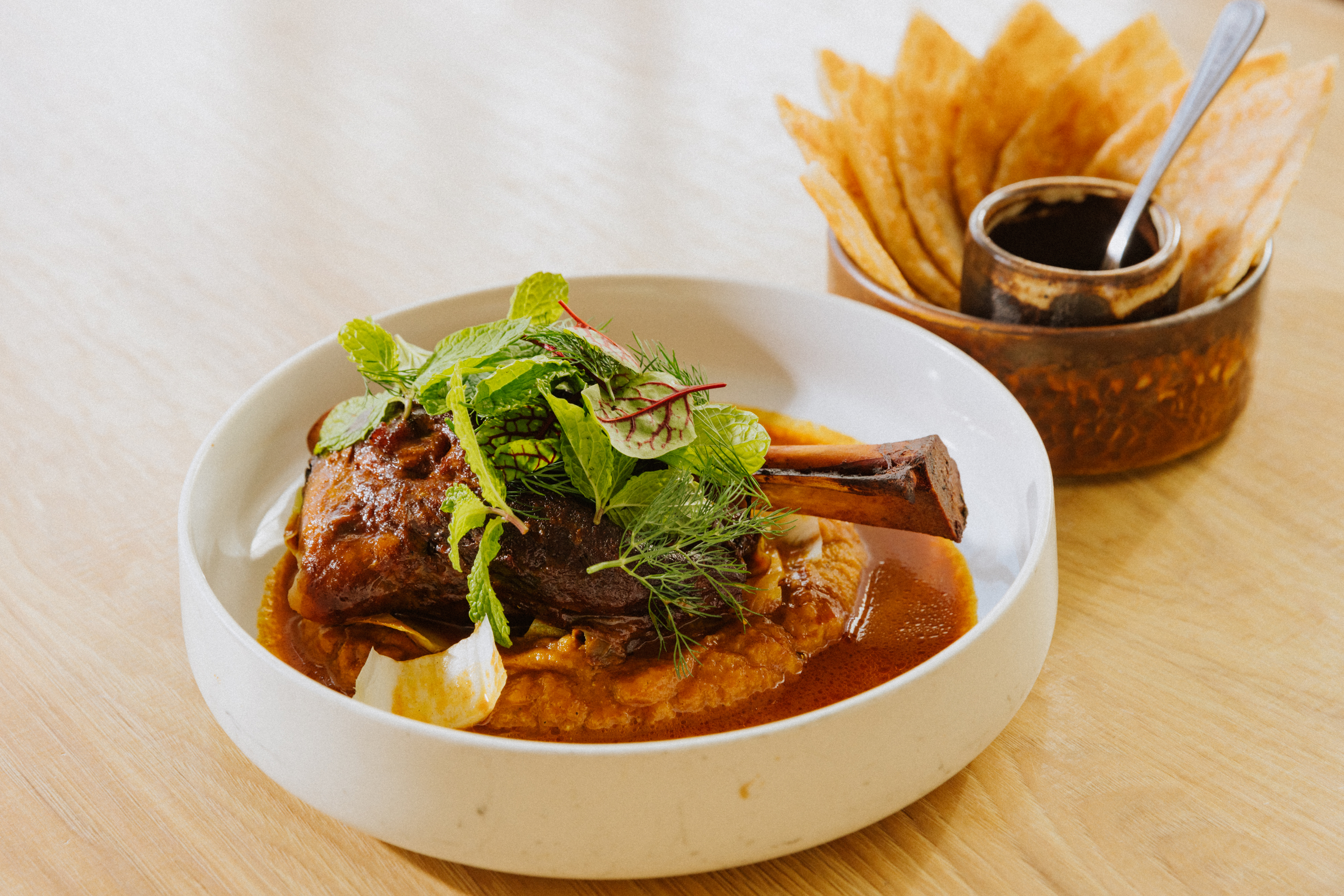 The braised lamb roti dish at Kothai Republic in San Francisco. The dish is made with Sichuan peppercorn sauce, charred eggplant, endive, and chili vinegar.