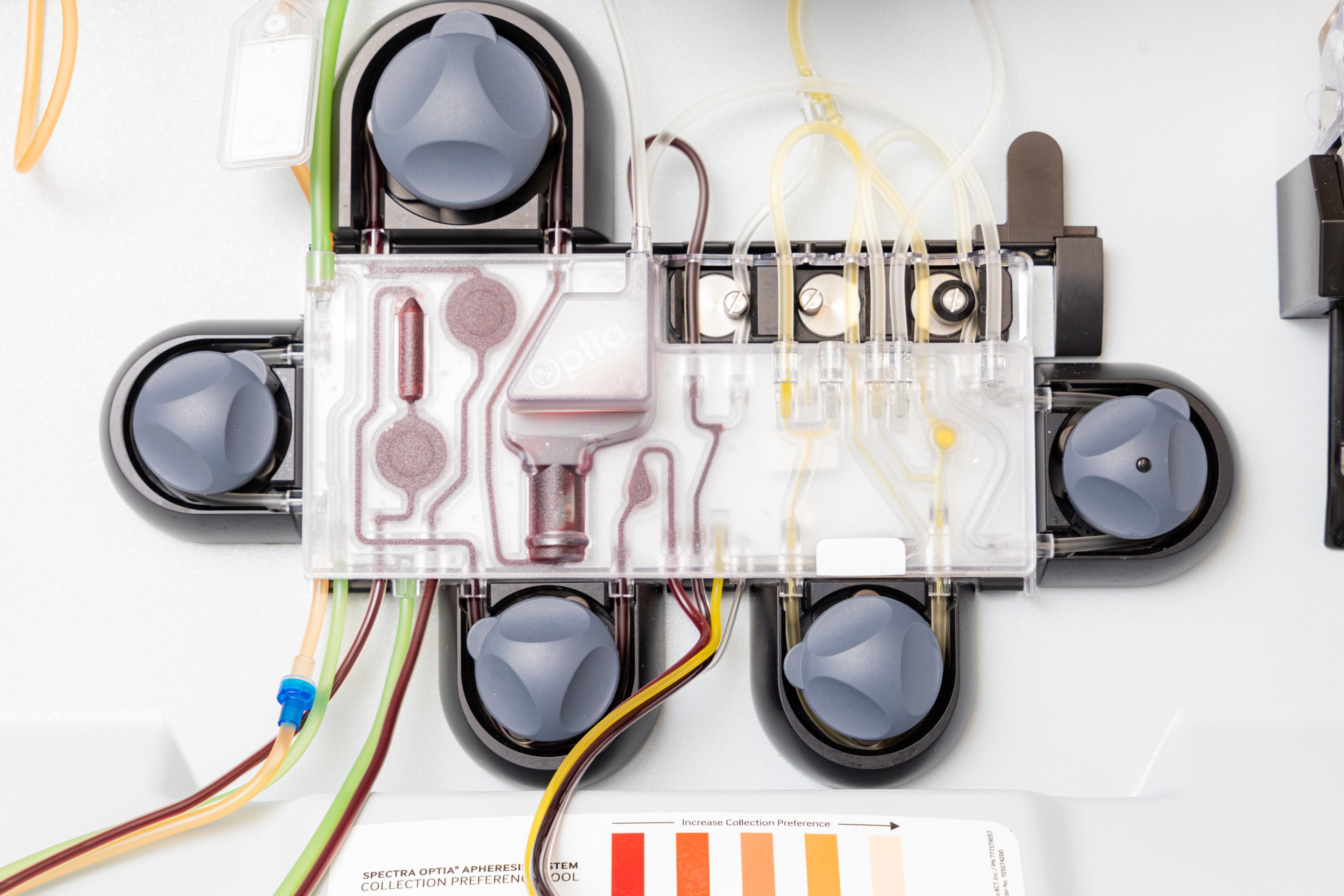 The image shows a medical device with several gray knobs, translucent tubes, and wires. It's likely part of a system used in health or lab settings.