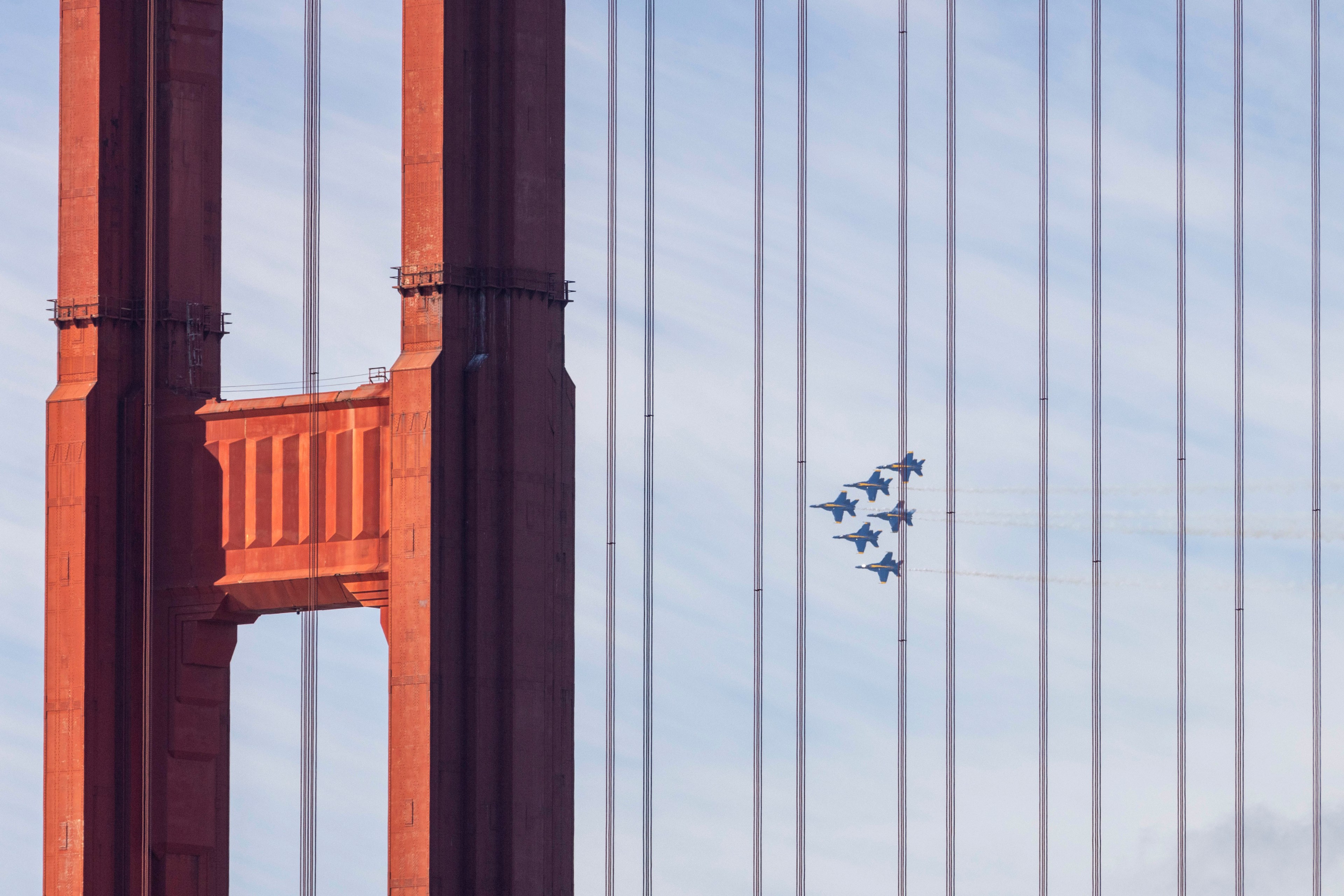 Blue jets soar behind the golden gate bridge.