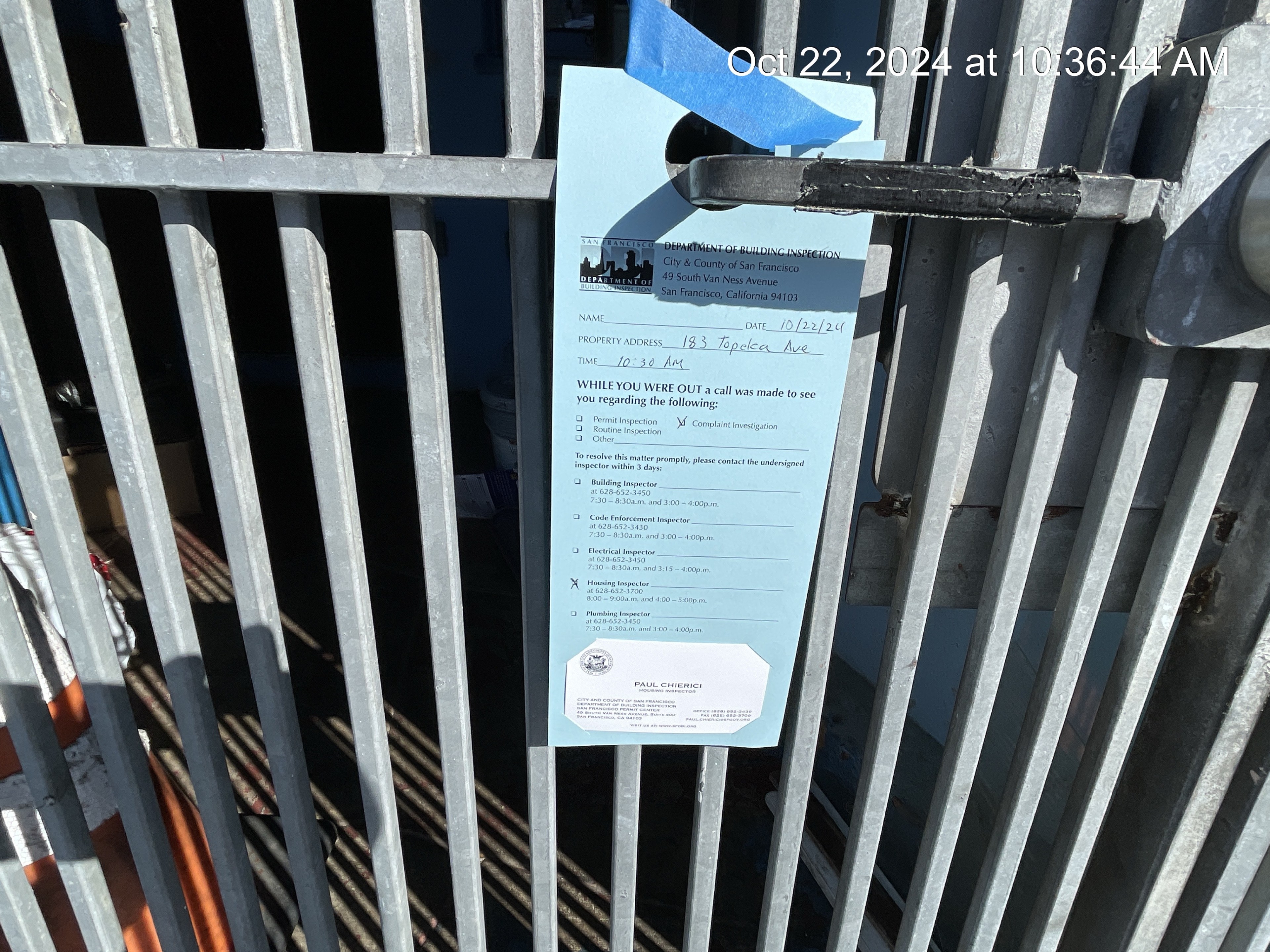 A blue notice is attached to a metal fence. It's from the San Francisco Department of Building Inspection, dated October 22, 2024, for 183 Topock Ave.