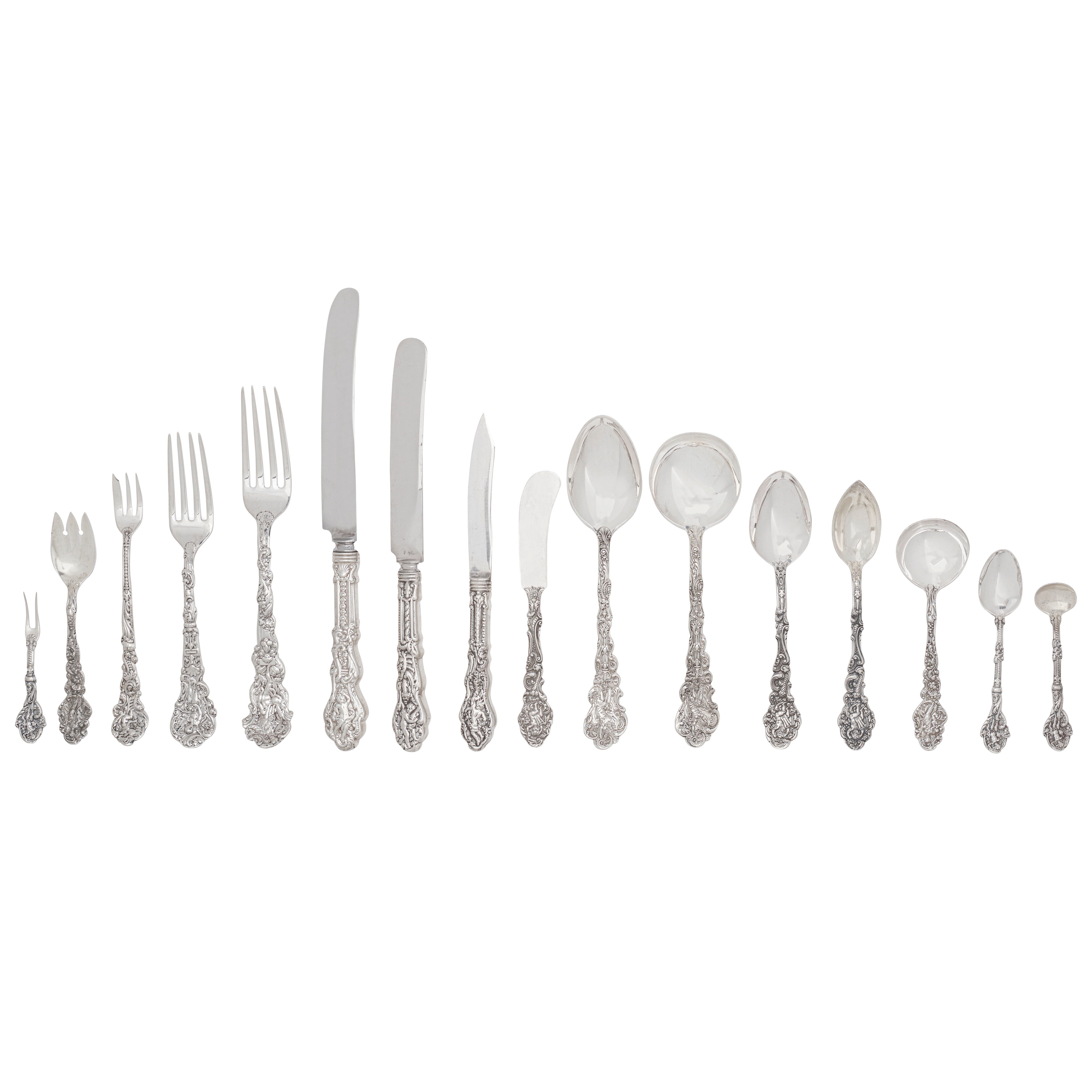 The image shows an elegant set of silver cutlery arranged in a line, featuring forks, knives, and various spoons with intricate ornate handles.