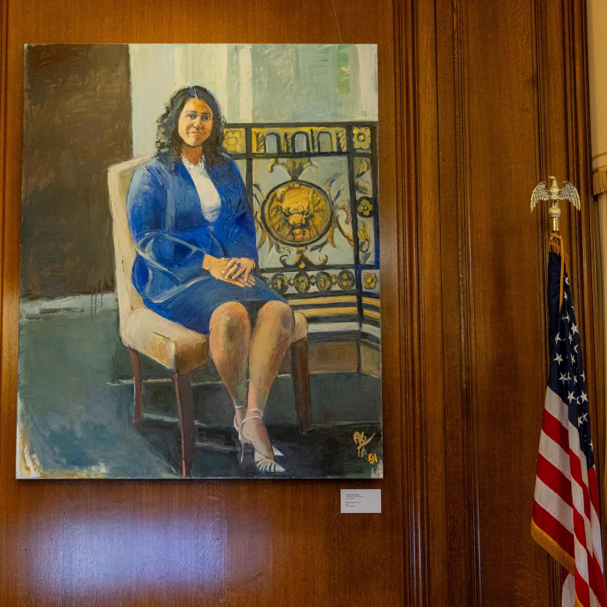 A portrait painting of a woman in a blue outfit sitting on a chair is displayed on a wooden wall. An American flag stands to the right.