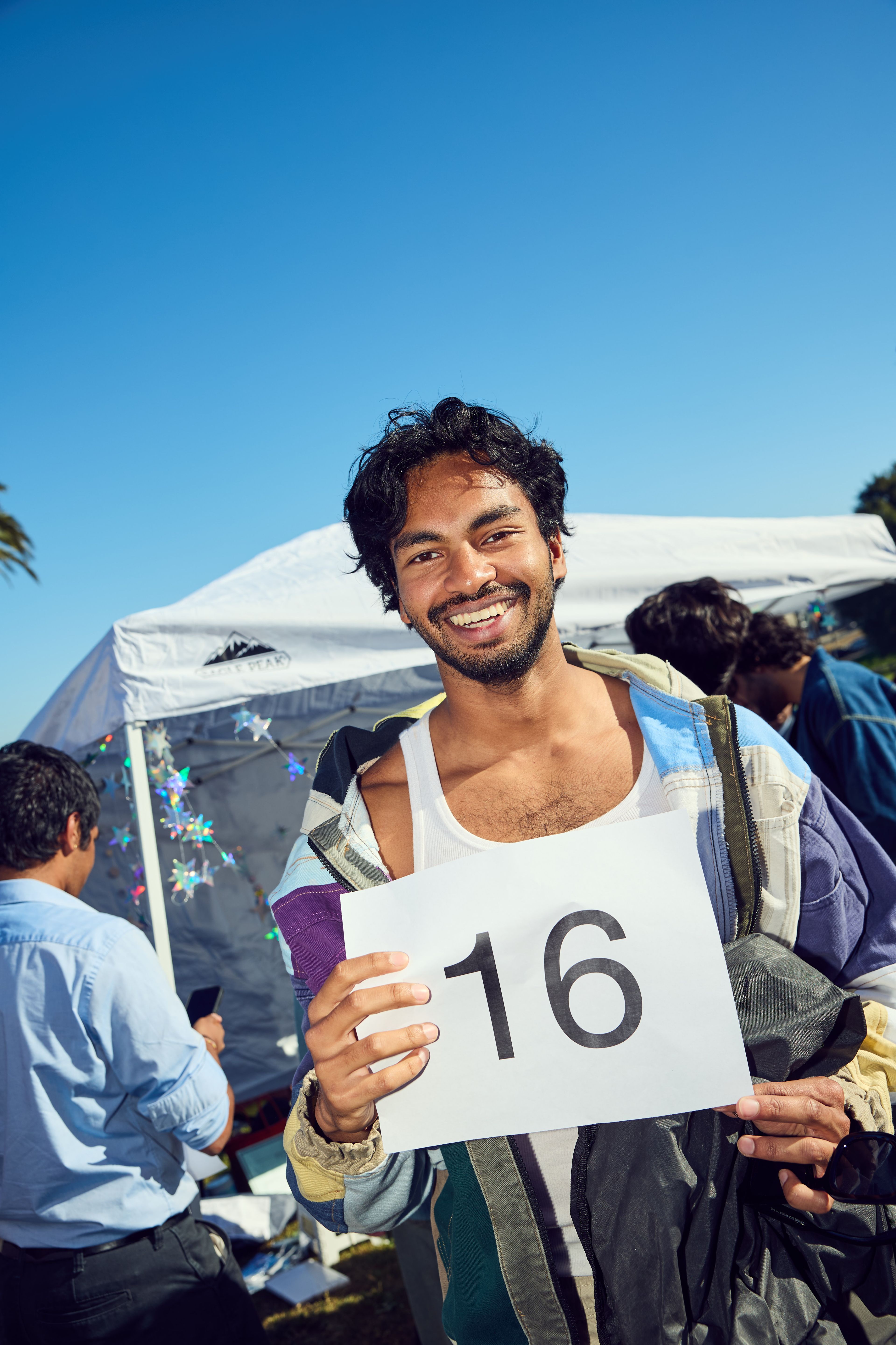 A man holds a sign with the number &quot;16&quot; on it.