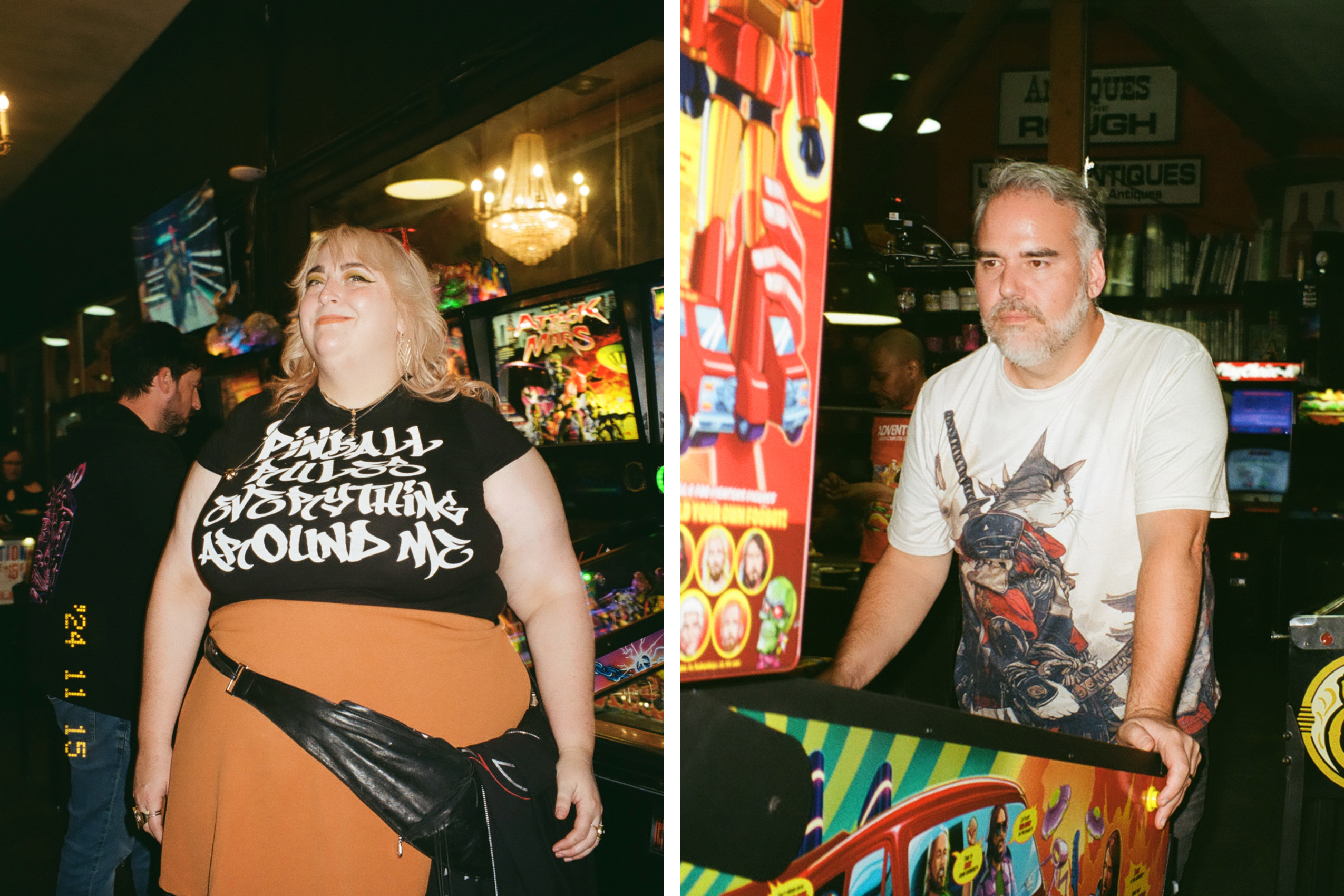 A person wearing a t-shirt with bold text stands in a vibrant arcade, and another person focuses intently on a pinball machine decorated with colorful graphics.