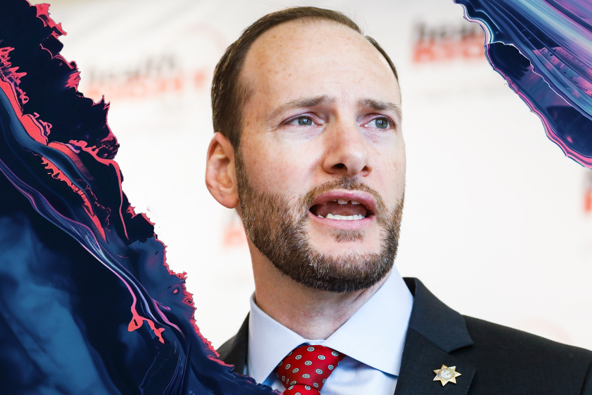 A man in a suit and tie speaks, looking to the side. He has a beard, and there's a colorful, abstract wave pattern surrounding the image.