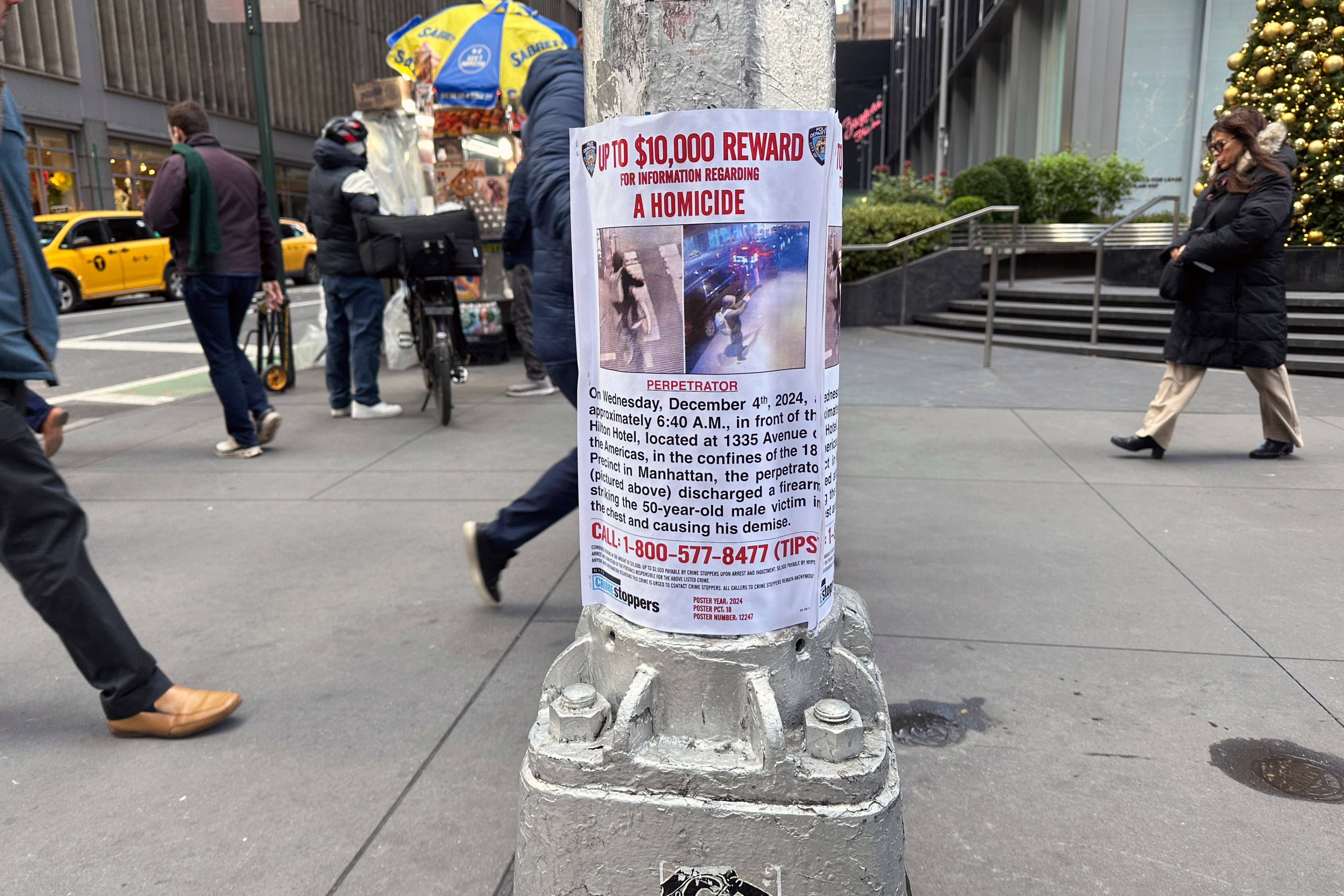 A reward poster on a pole offers up to $10,000 for information on a homicide. It includes images of the suspect and details about the incident, with a tip line number.