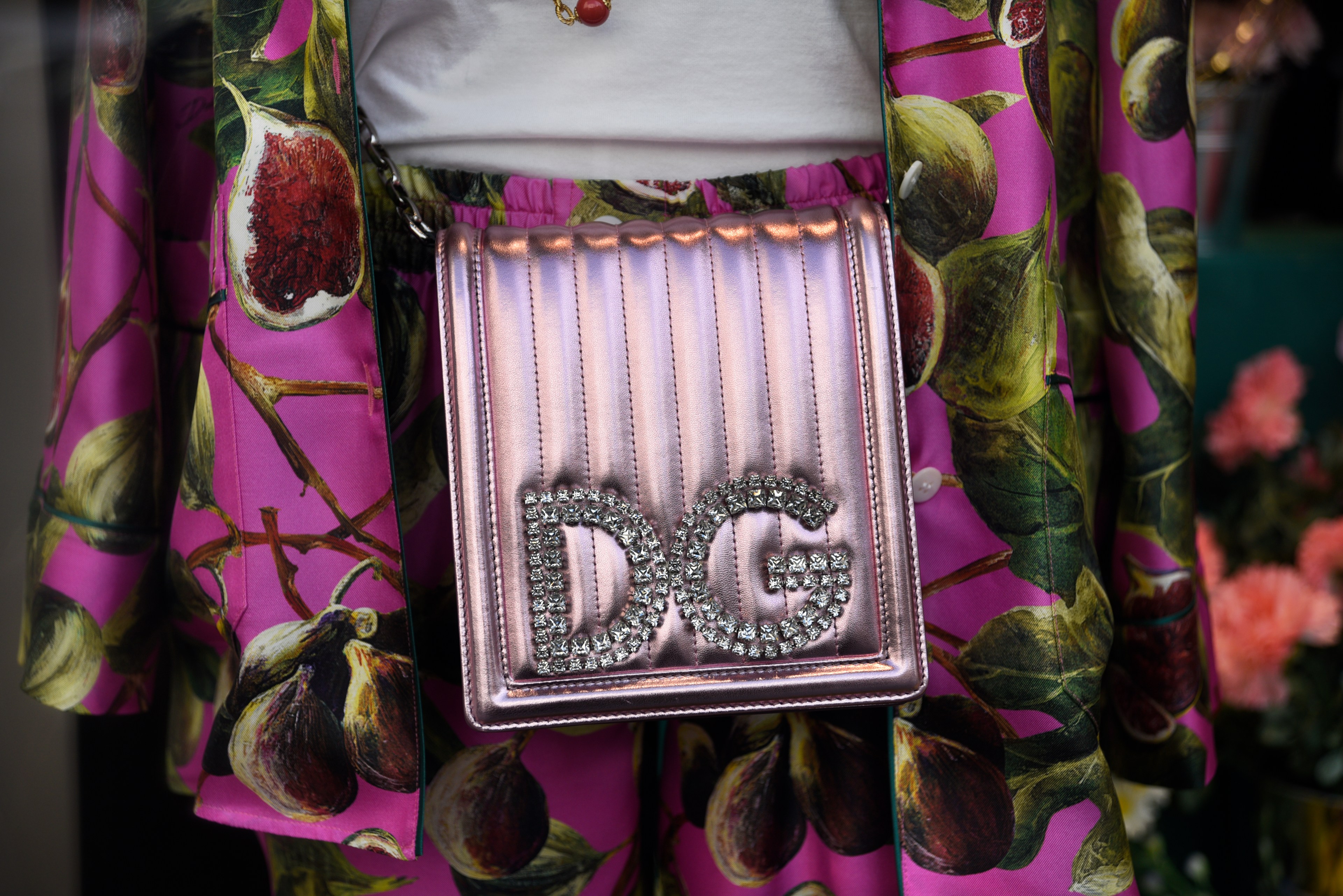 A pink metallic bag with &quot;DG&quot; in rhinestones over a fig-patterned skirt and jacket set.