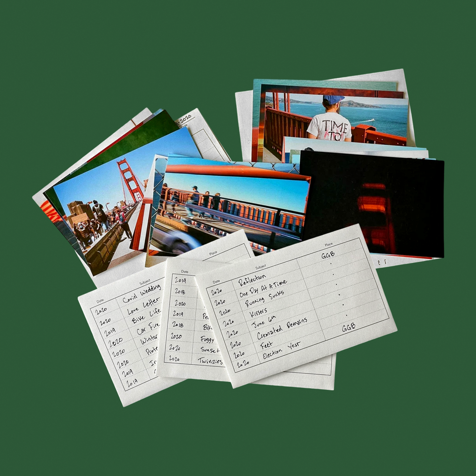 A stack of photos featuring the Golden Gate Bridge is displayed alongside handwritten cards listing dates, subjects, and places related to the images.