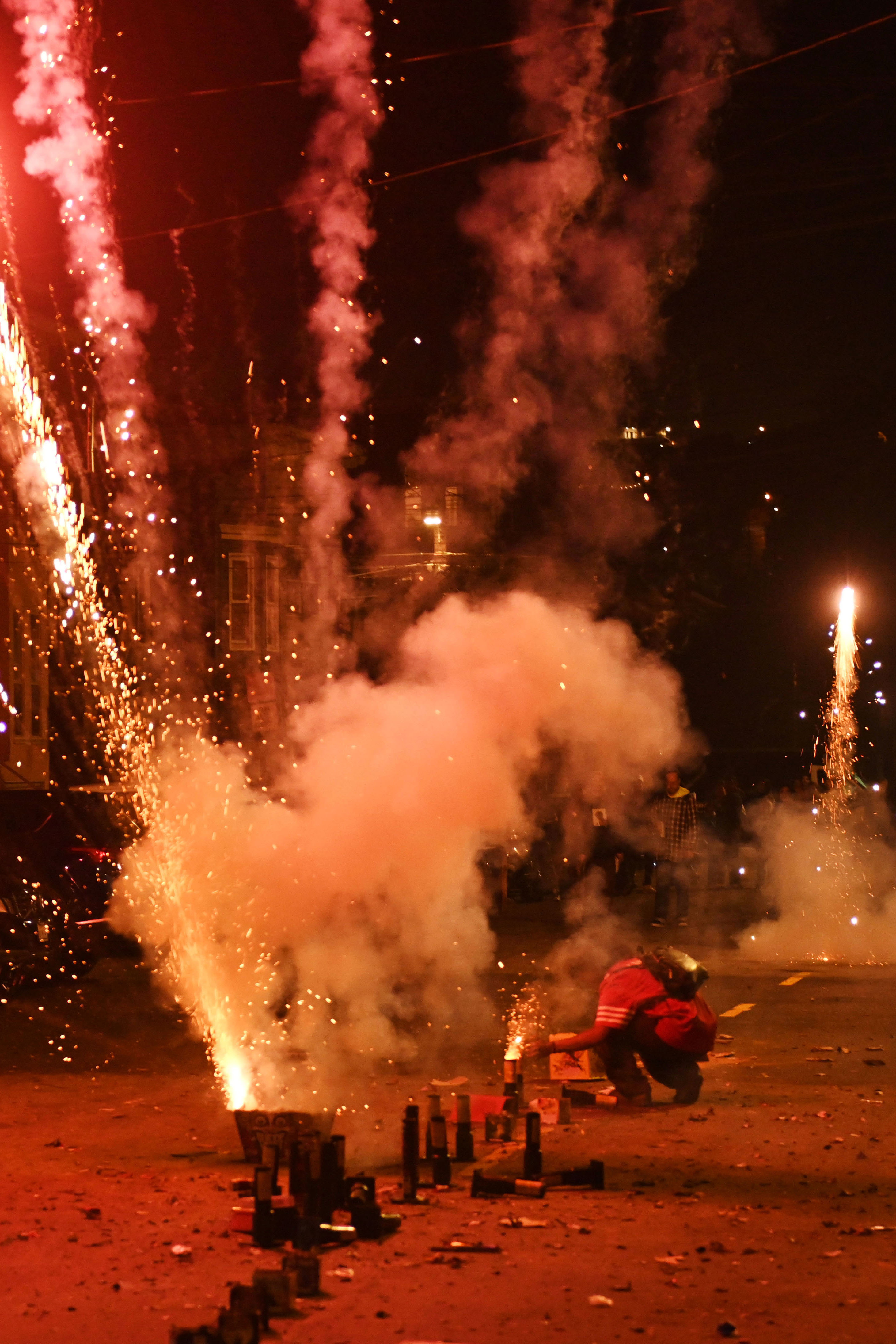 A man ignites a firework while other fireworks explode around him near Garfield Square in San Francisco on Thursday, July 4, 2024. Every year, despite their illegality in many Bay Area communities, fireworks illuminate the skies on the Fourth of July holiday. Local fire departments issue annual warnings about the risks of personal injuries and forest fires, particularly in the hills where dry vegetation fuels rapid spreads. This year, new city, county, and state measures focus on readiness, stricter penalties for violators, and critical evaluations of fireworks' impact and associated policies.