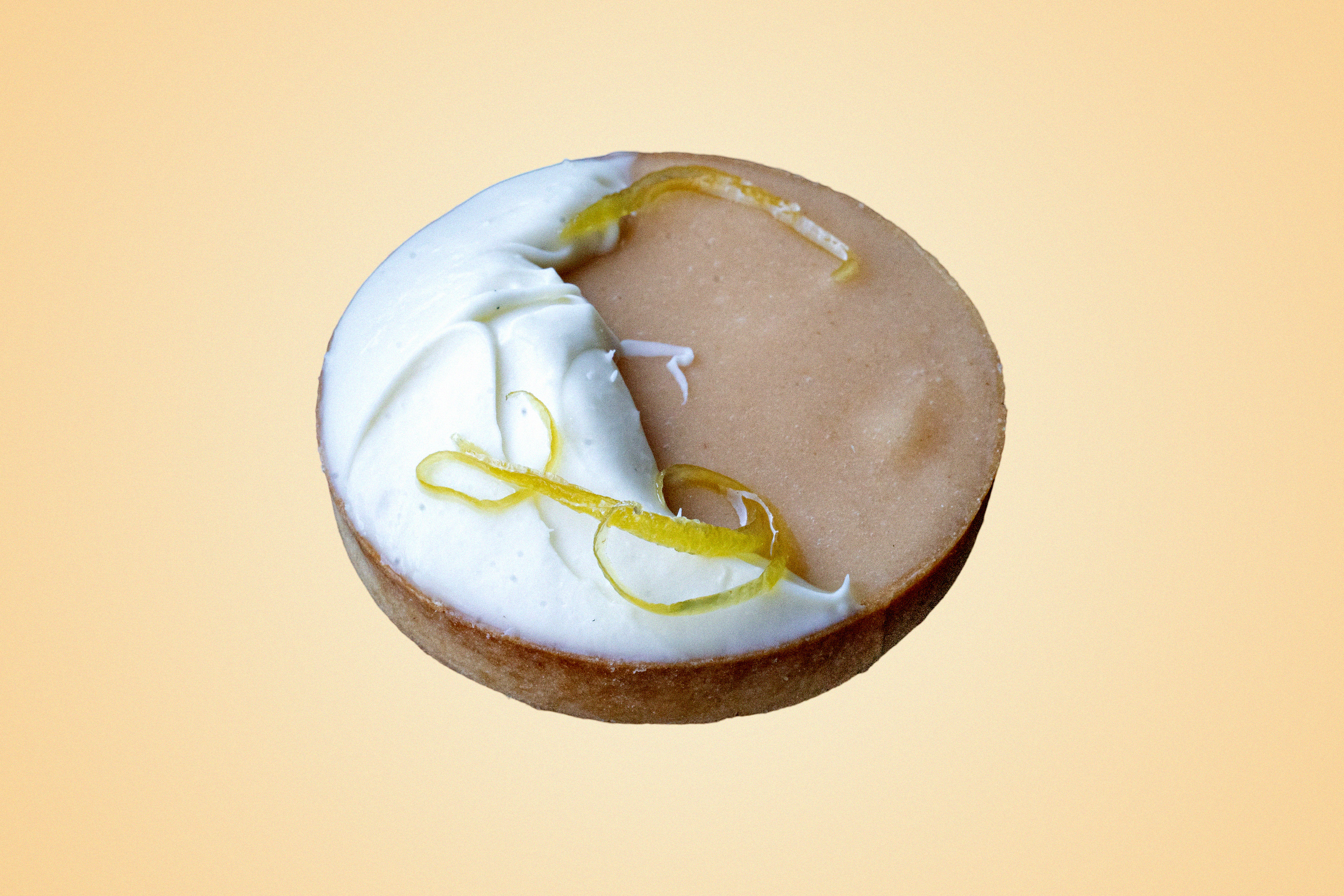 A delicious circular shaped tart with white cream and lemon shavings.