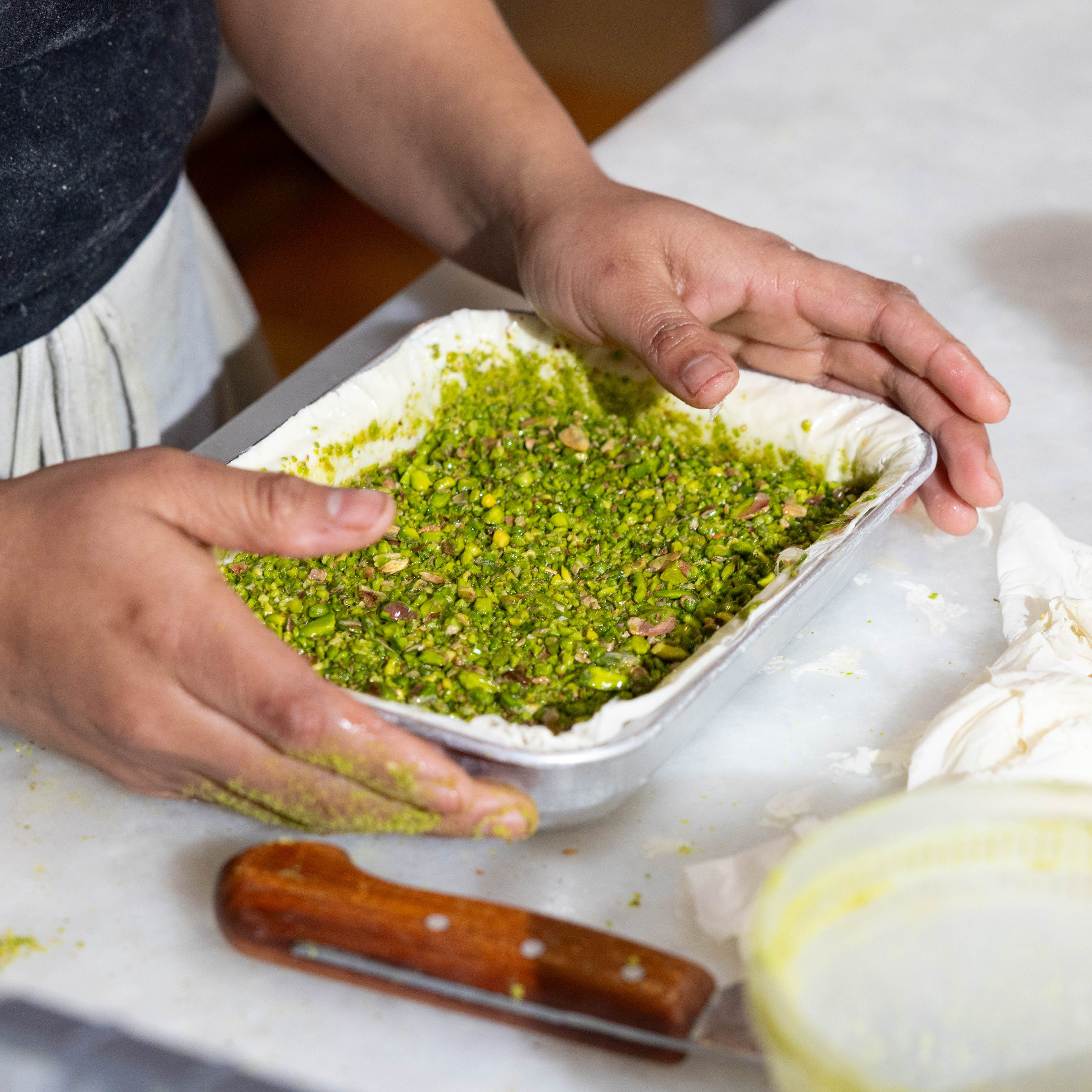 The pistachios are being filled in the baklava.