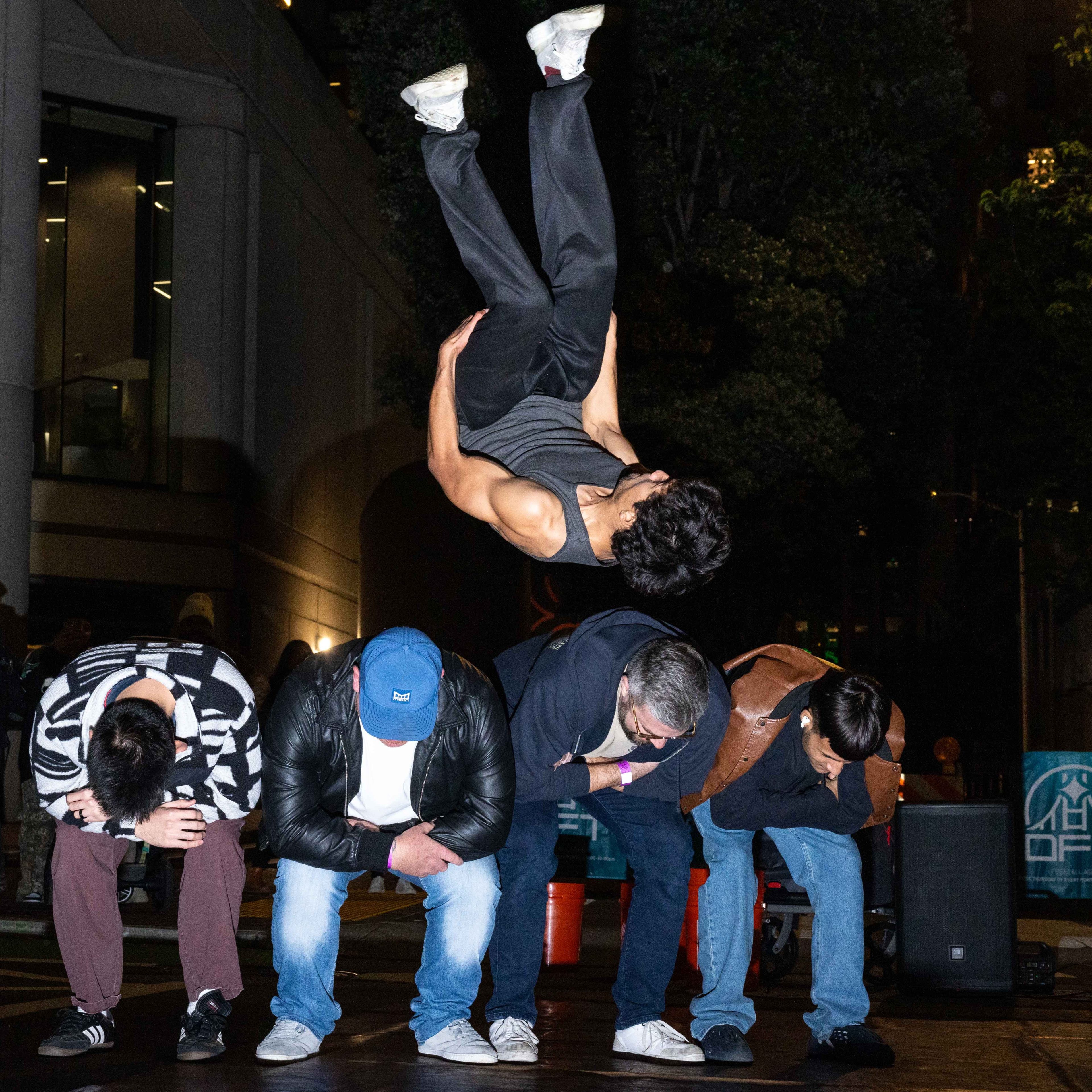 A man does a backflip over four of his friends