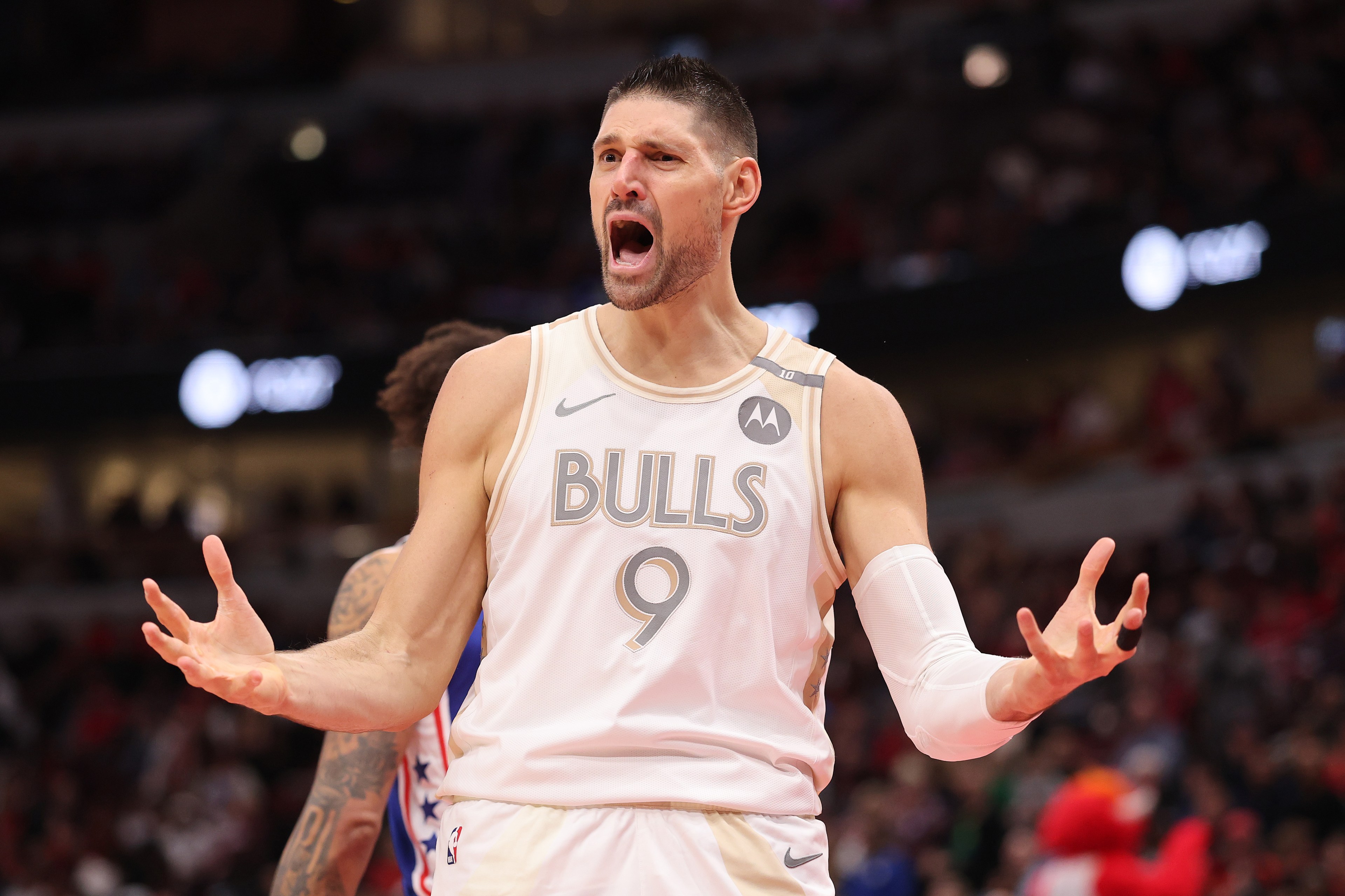 A basketball player in a white Bulls jersey, numbered 9, appears animated and expressive on the court, with a crowd blurred in the background.