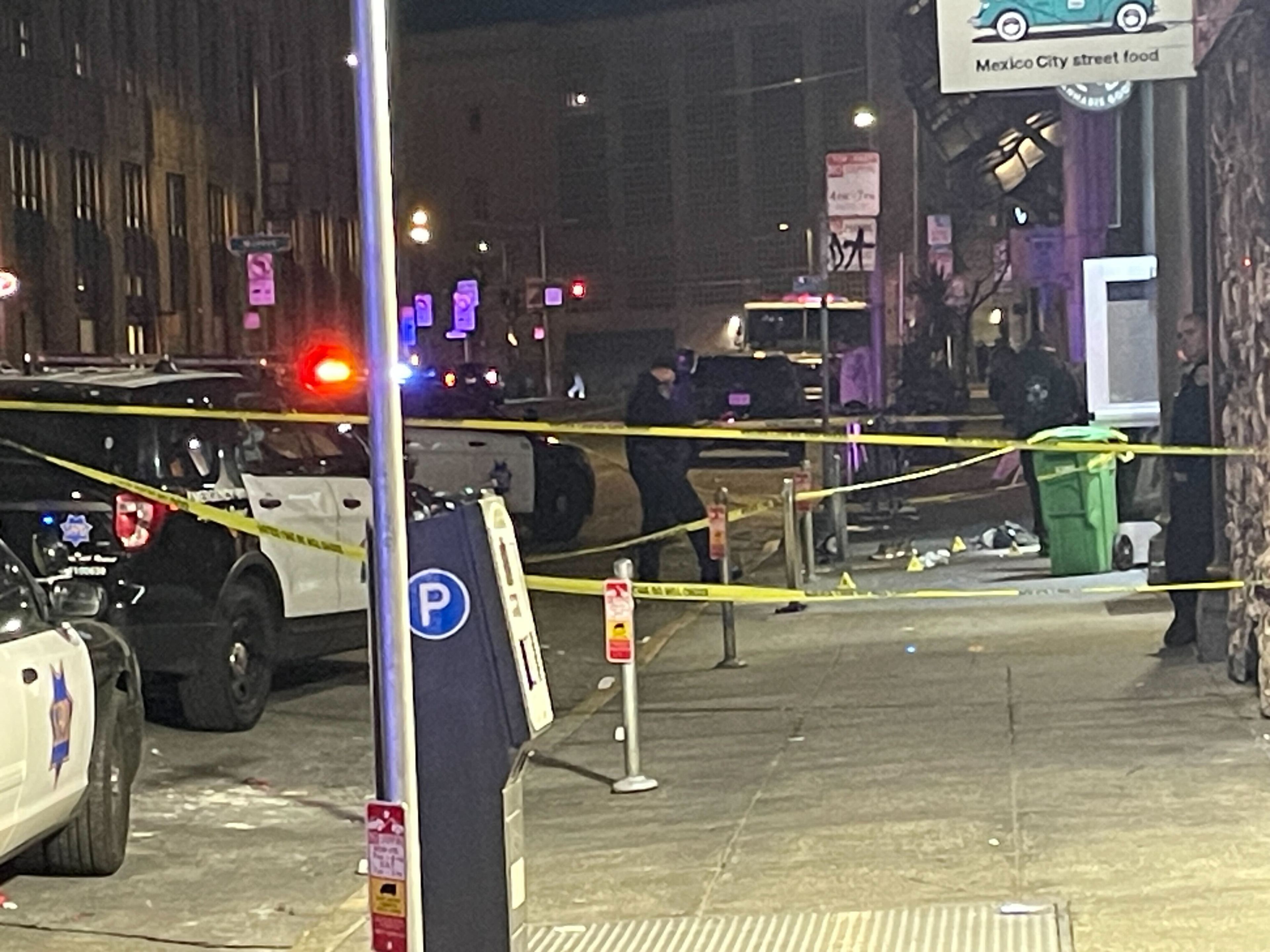 The image shows a nighttime street scene with police cars, flashing lights, and yellow caution tape blocking the area. A street sign mentions &quot;Mexico City street food.&quot;