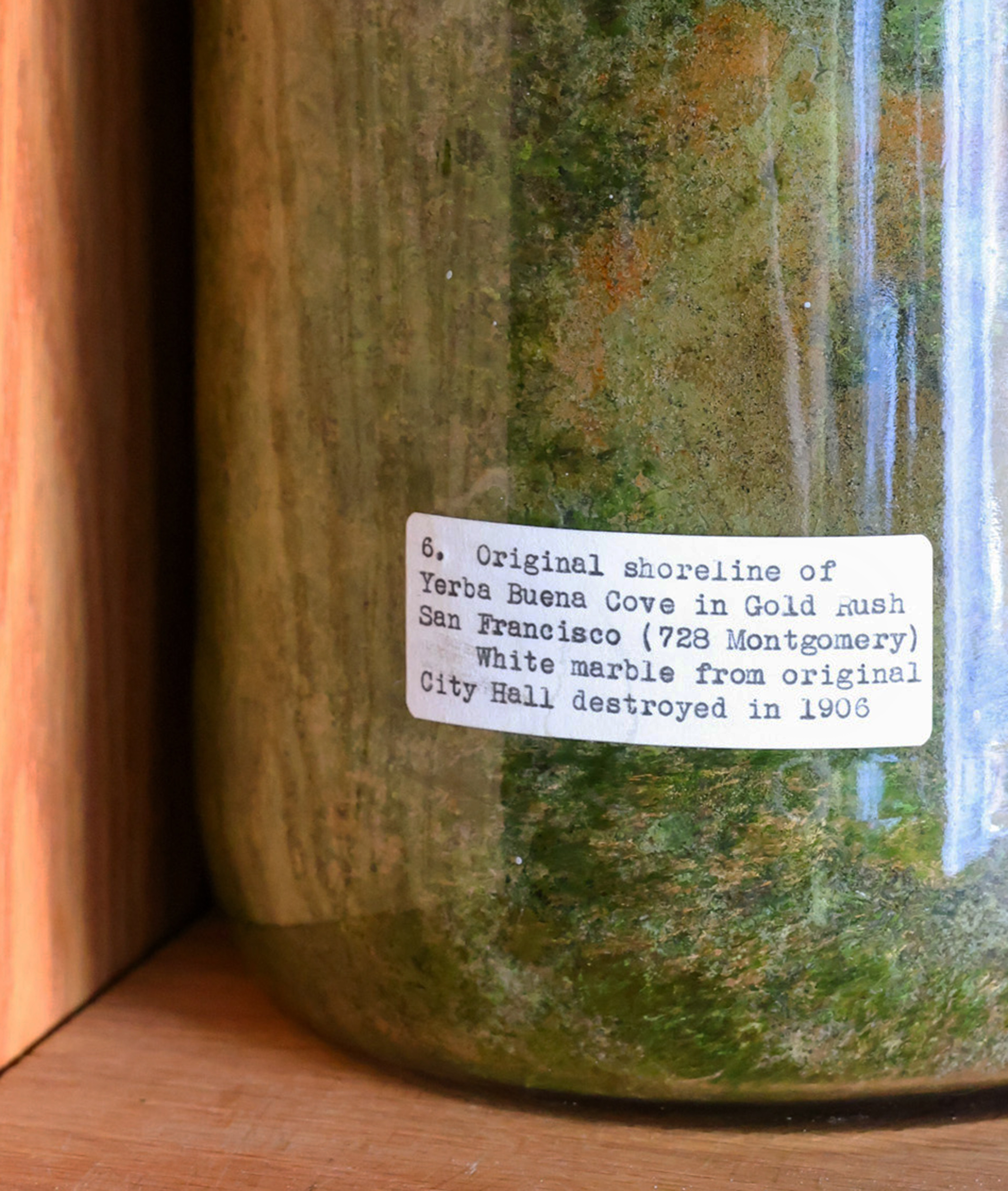 The image shows a jar with a label describing it as containing a piece of the original shoreline of Yerba Buena Cove from the Gold Rush era in San Francisco.