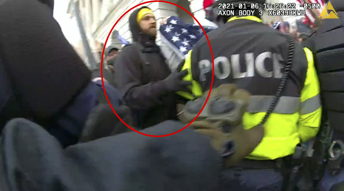 A person in a yellow hat holds a flag beside a police officer in a reflective jacket amidst a crowded scene. The timestamp and "AXON BODY" are visible.