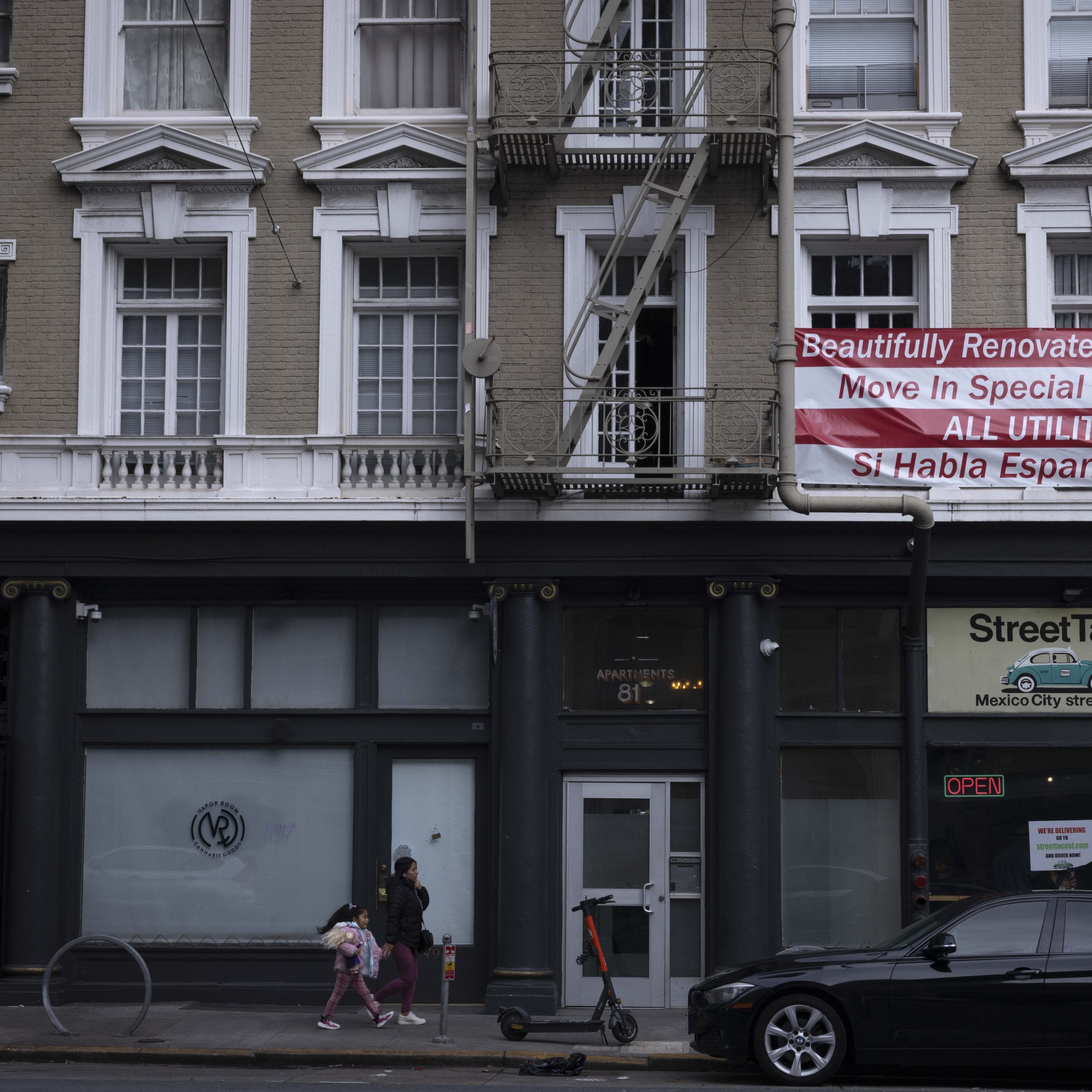 A street scene shows a classic building with a &quot;Beautifully Renovated&quot; banner, a woman and child walking, and a parked black car nearby.