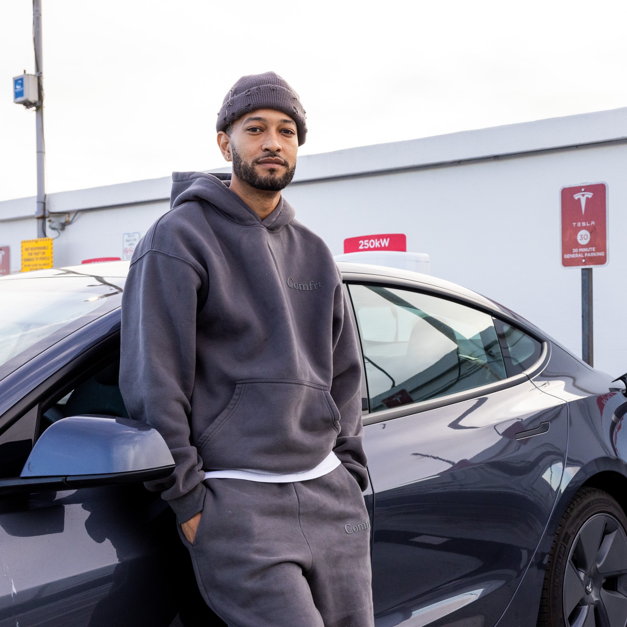 A man poses in front of his car