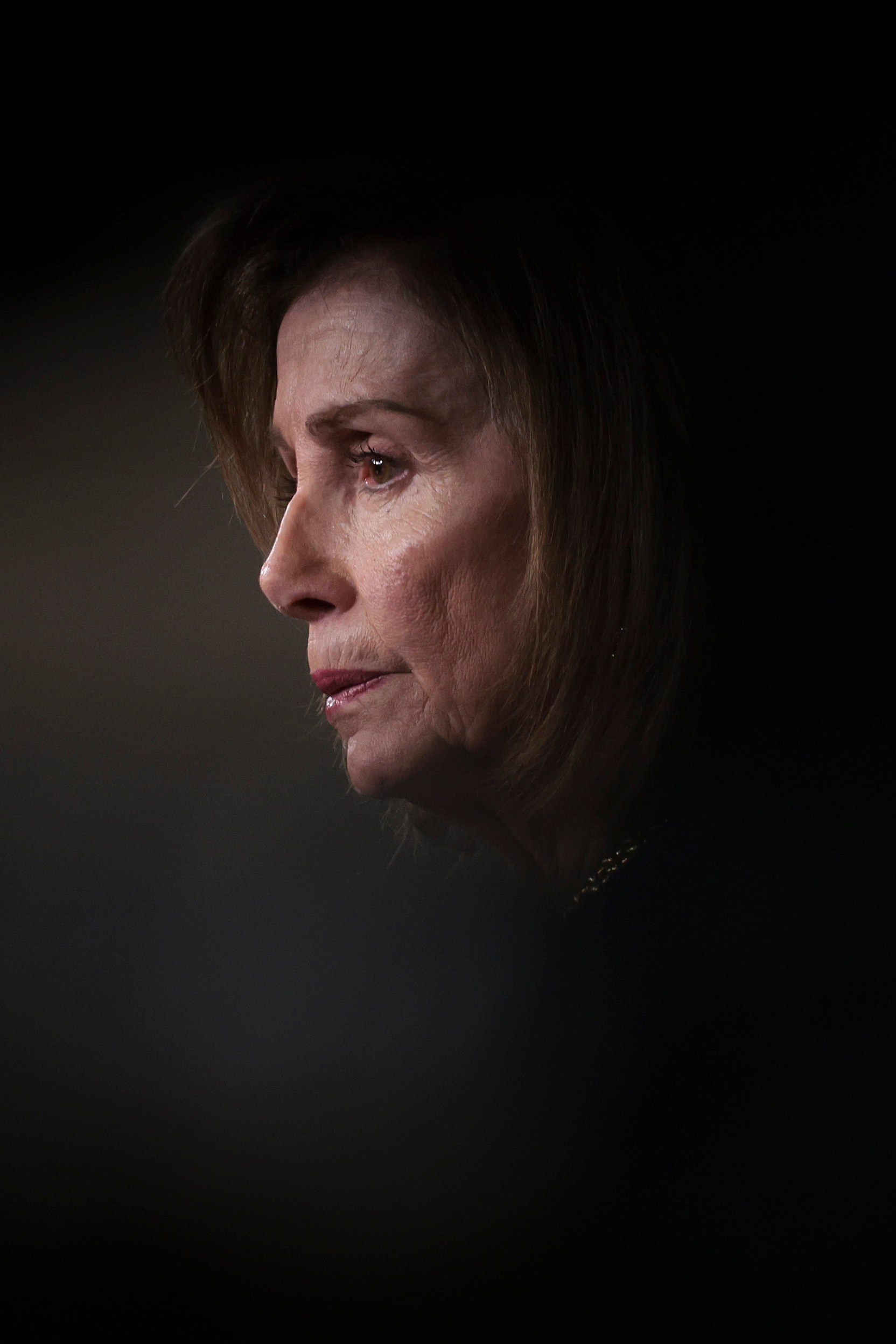 A person is seen in profile with soft lighting highlighting their face against a dark, blurred background. The expression appears contemplative.