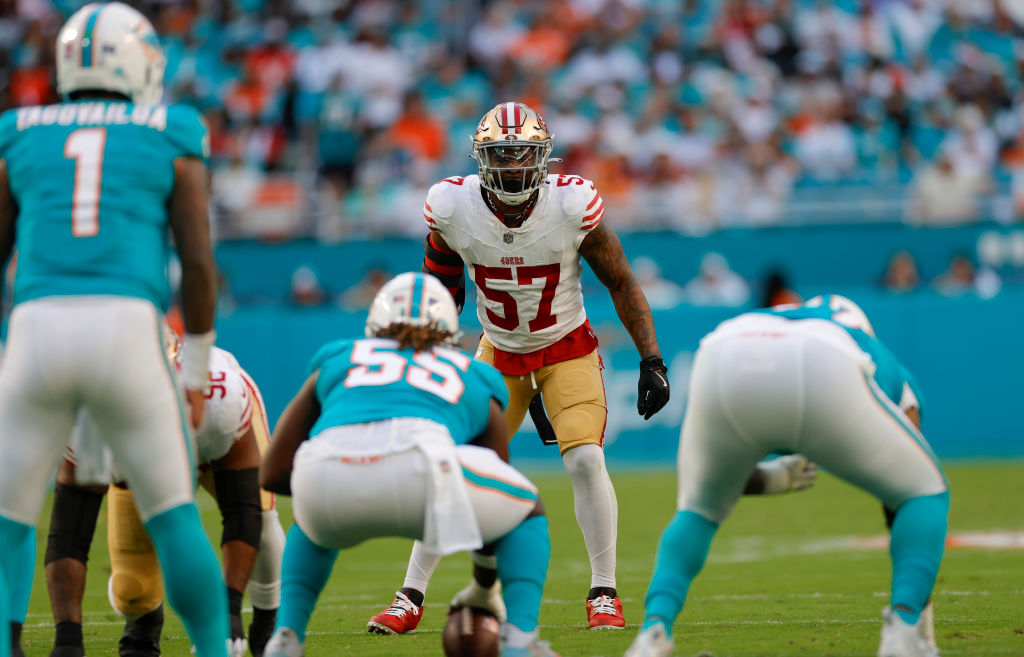 A football game scene shows players from two teams in a ready stance. One team wears teal jerseys, and the other team has red and gold uniforms.