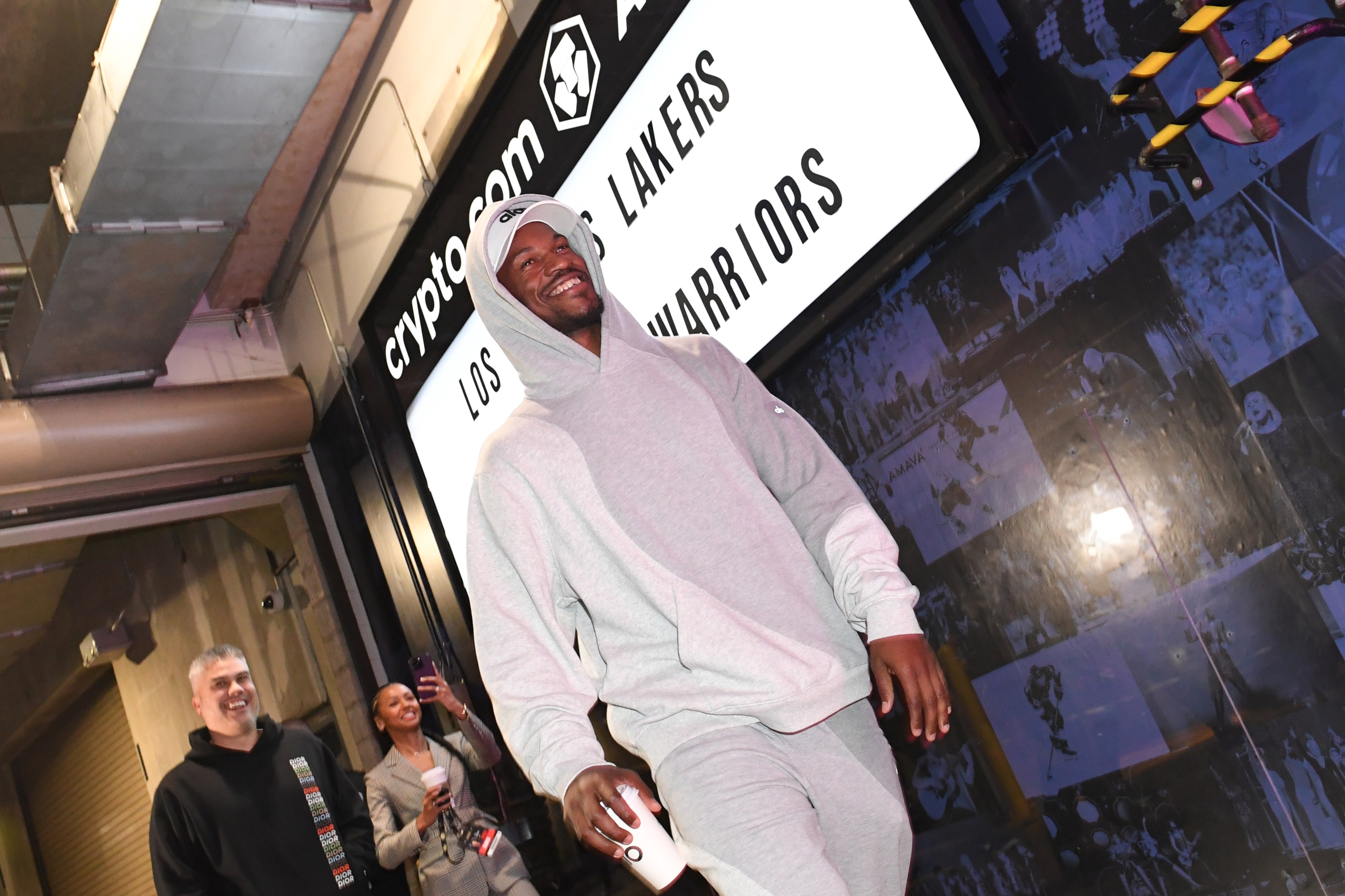 A man wearing sweatpants walking with a cup.