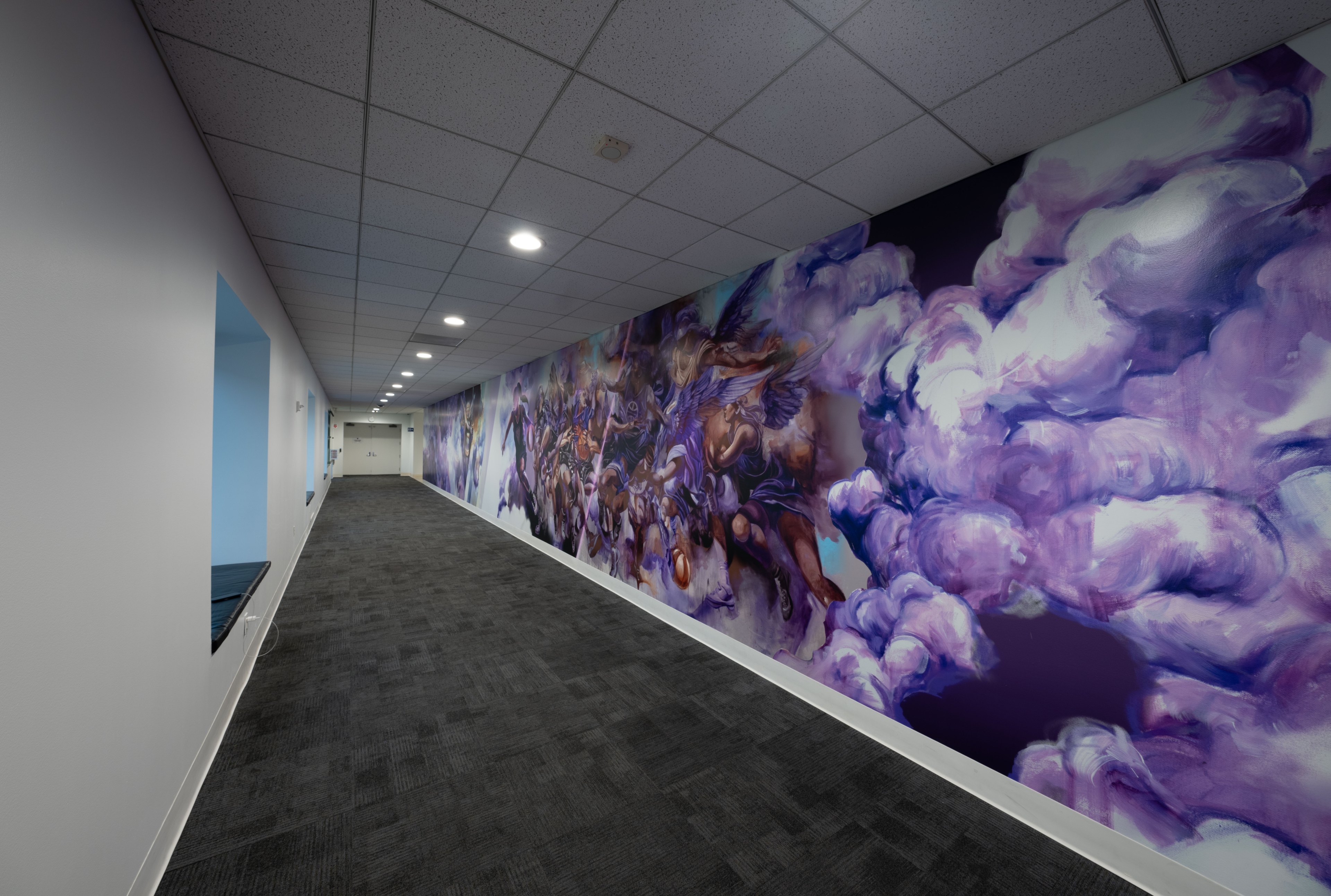 A long corridor with a vibrant mural on the right wall, featuring dynamic purples and blues, depicting fantastical figures and clouds in a dramatic scene.