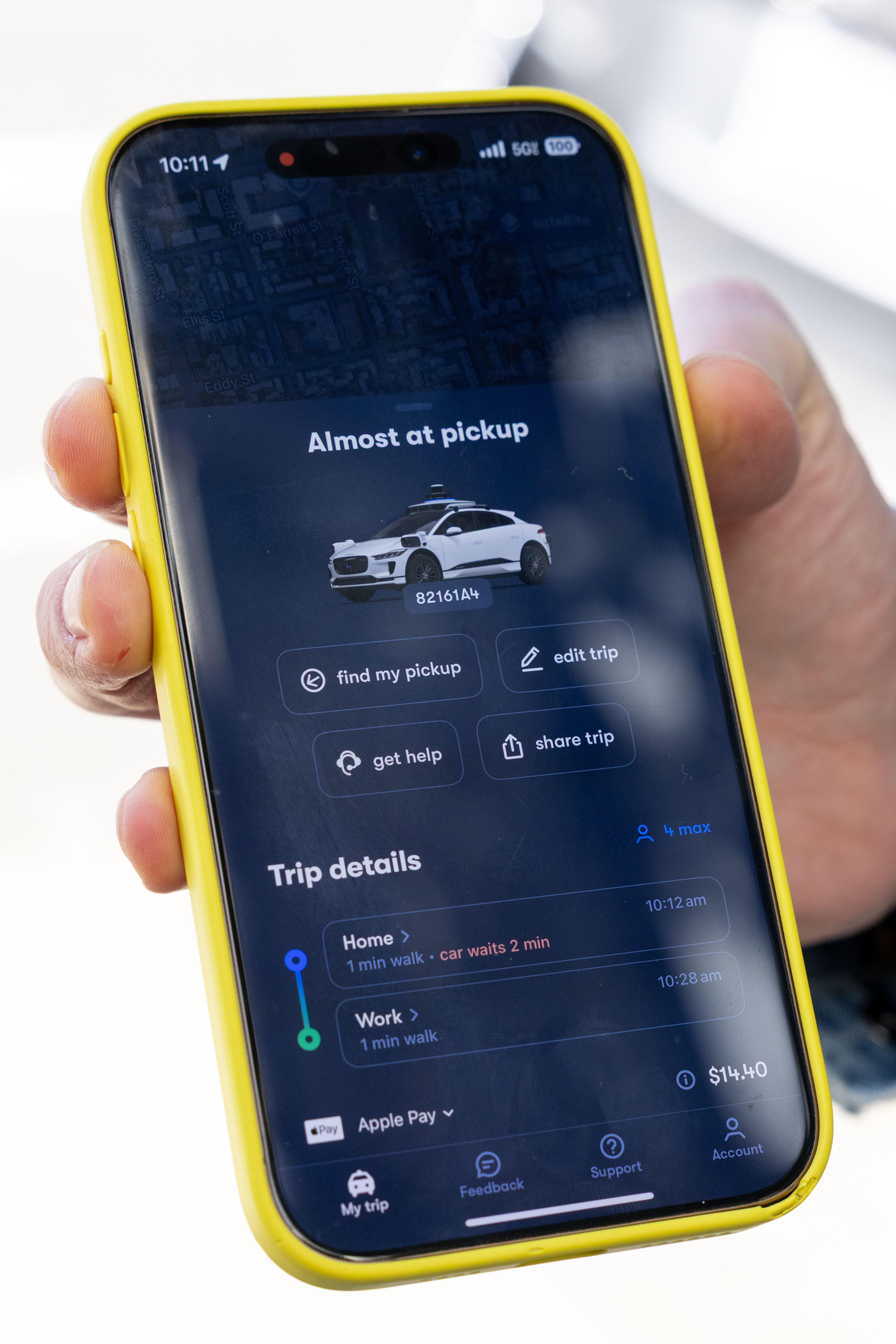 A smartphone displays a ride-hailing app, showing a car almost at pickup. Details include trip info from Home to Work, costing $14.40, with various options.