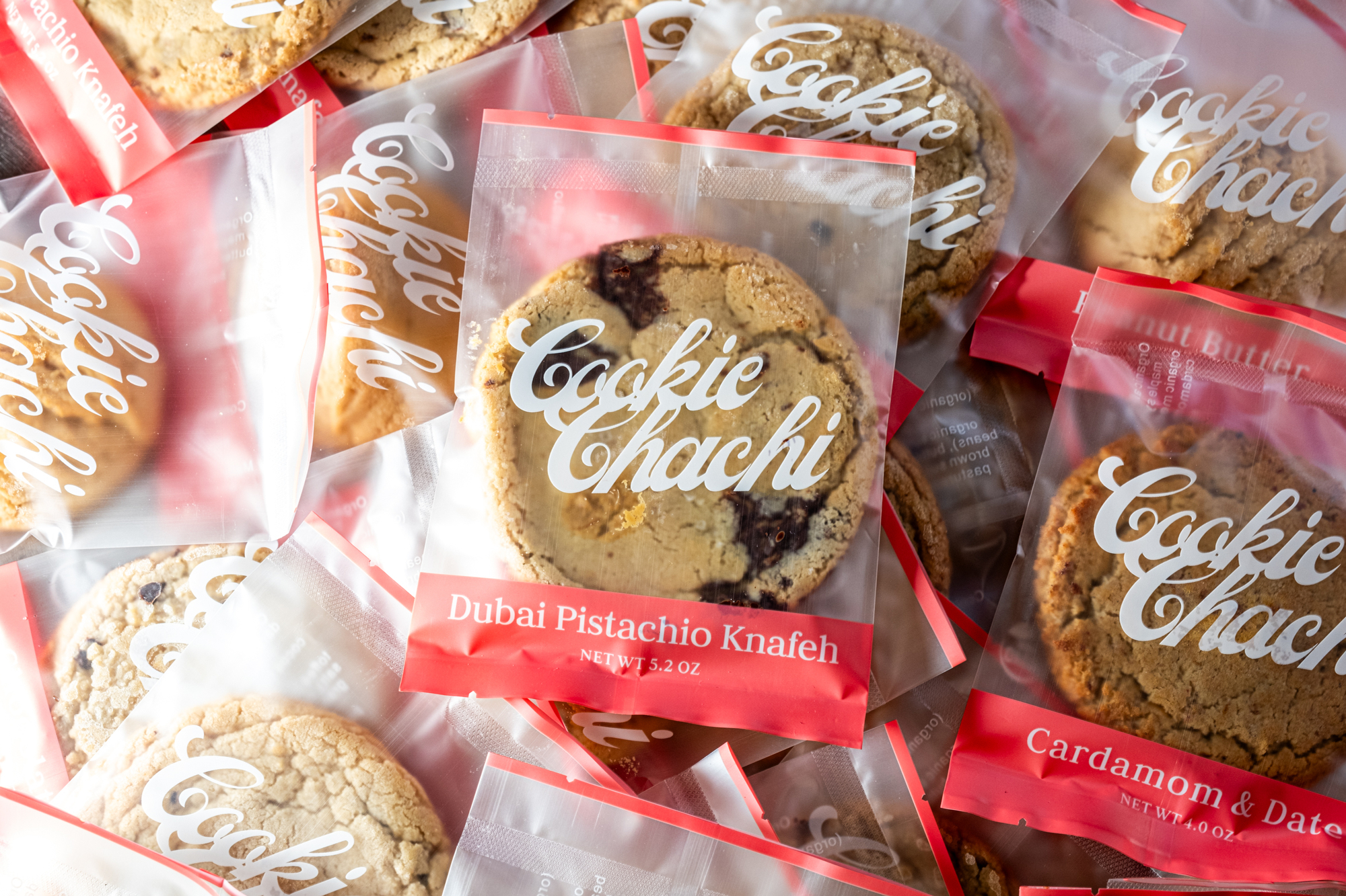 The image shows several packaged cookies labeled &quot;Cookie Chachi,&quot; with flavors like &quot;Dubai Pistachio Knafeh&quot; and &quot;Cardamom &amp; Date&quot; visible.